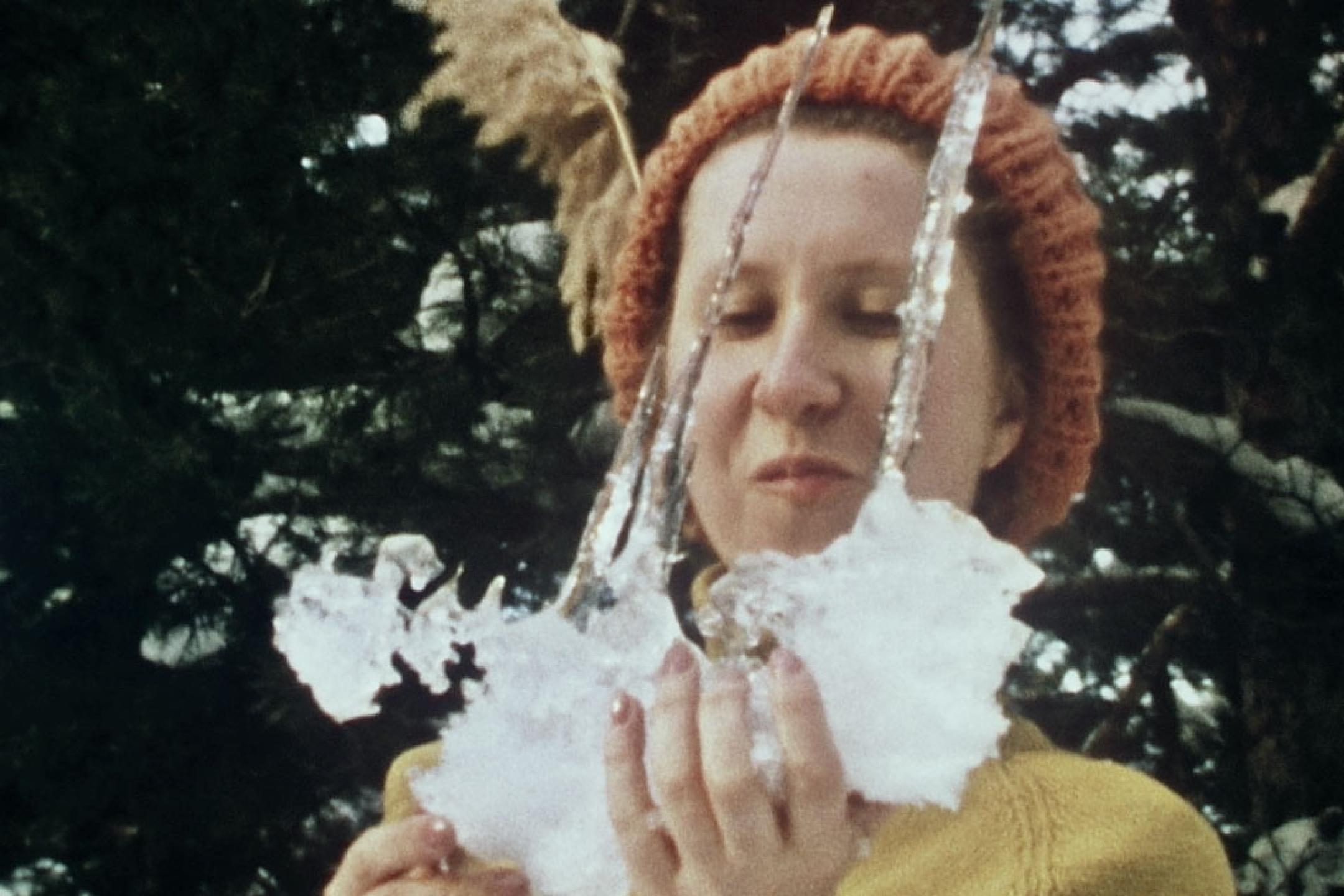 A woman with a beanie holds a piece of icicles.