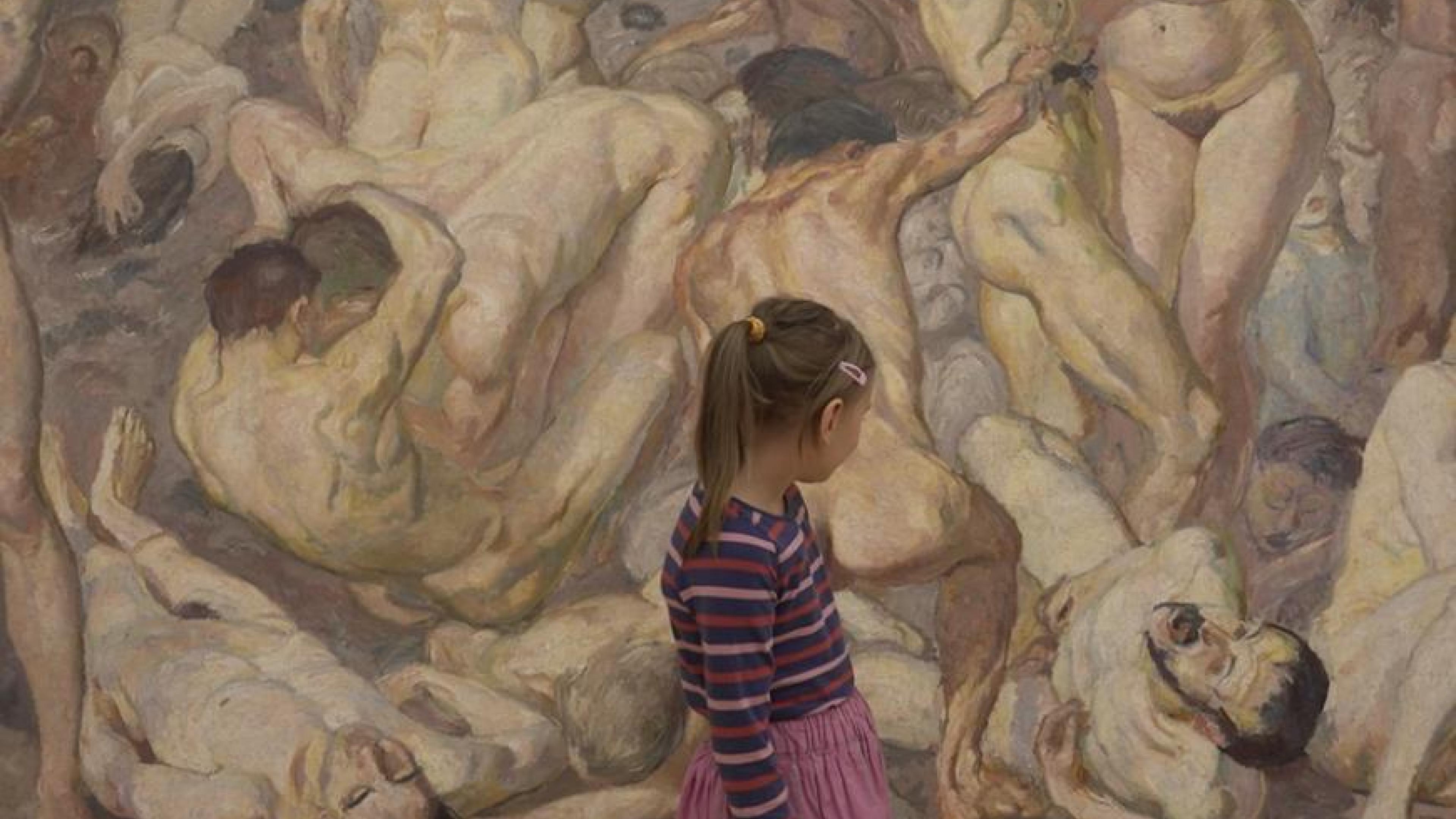Ein junges Mädchen in geringeltem Pulli und Rock steht vor einem riesigen Gemälde, das viele nackte, verschlungene Menschen zeigt