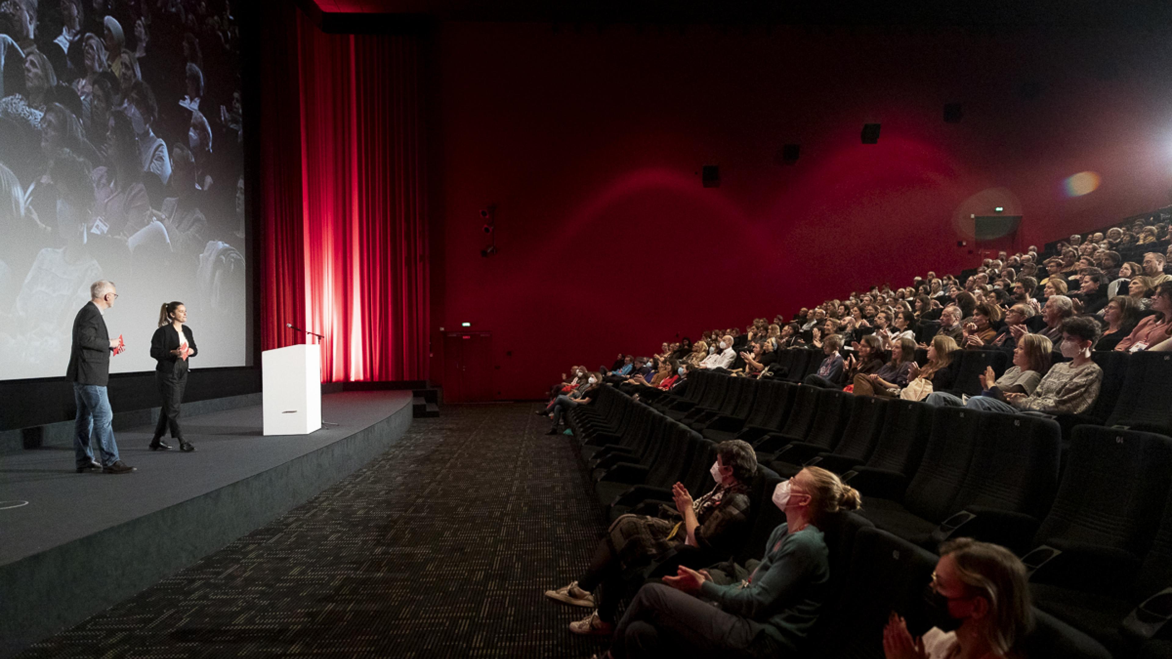 Viele Menschen mit Mund-Nase-Bedeckung im Kinosaal bei der Eröffnung von DOK Leipzig 2021