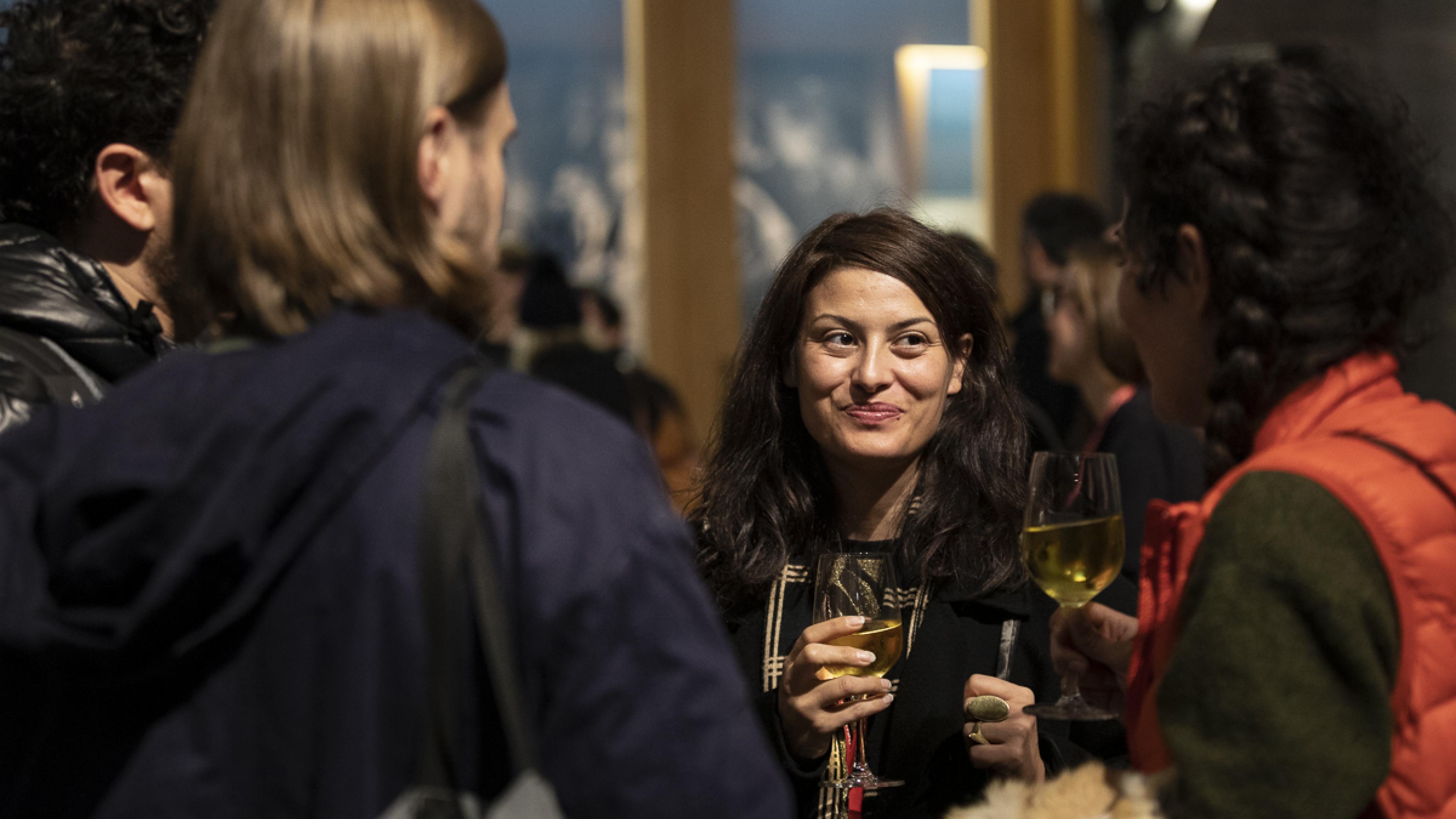 A group of four persons standing close to each other and chatting at a festival reception.