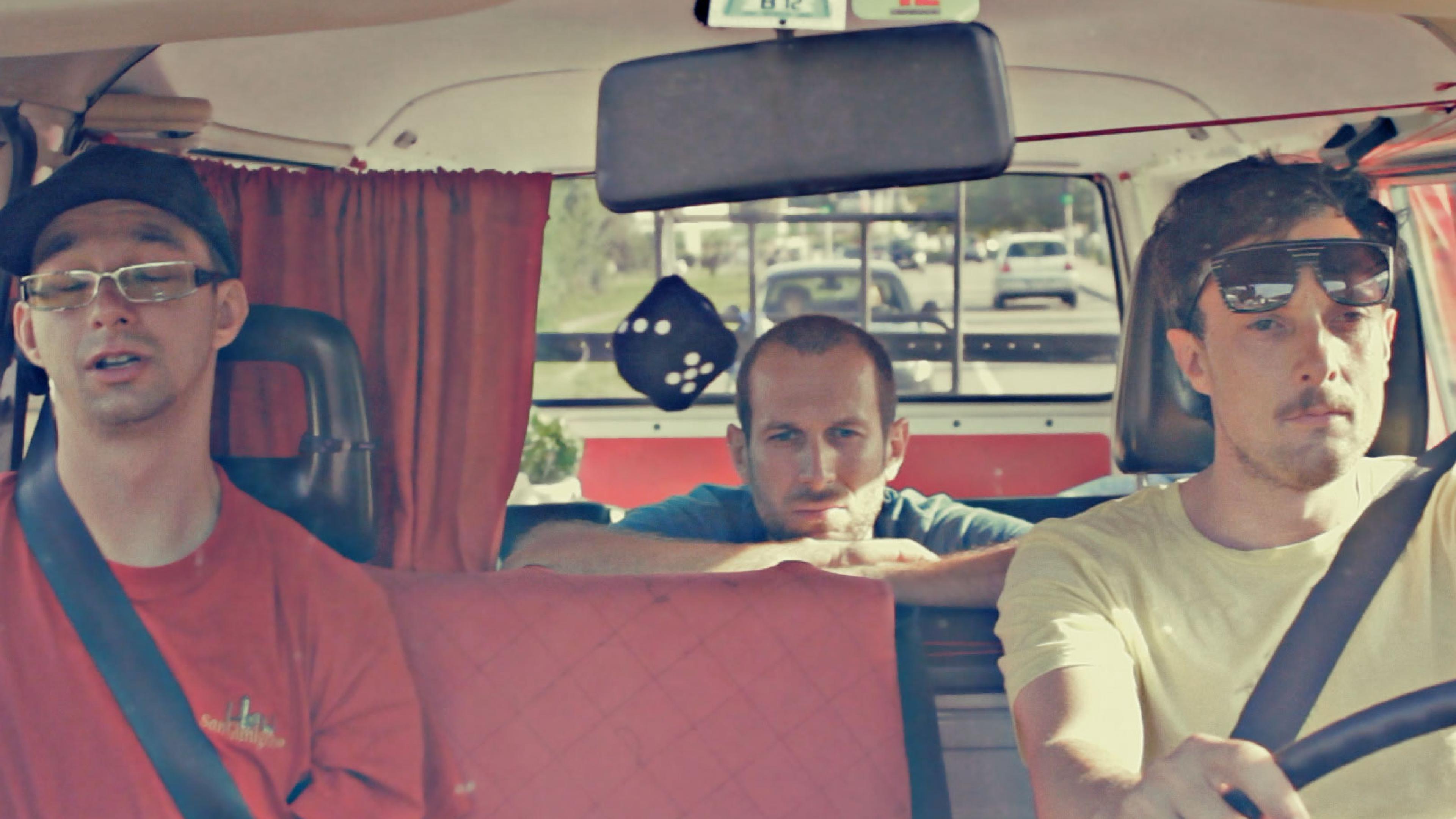 Drei Männer sitzen in einem VW-Bus.