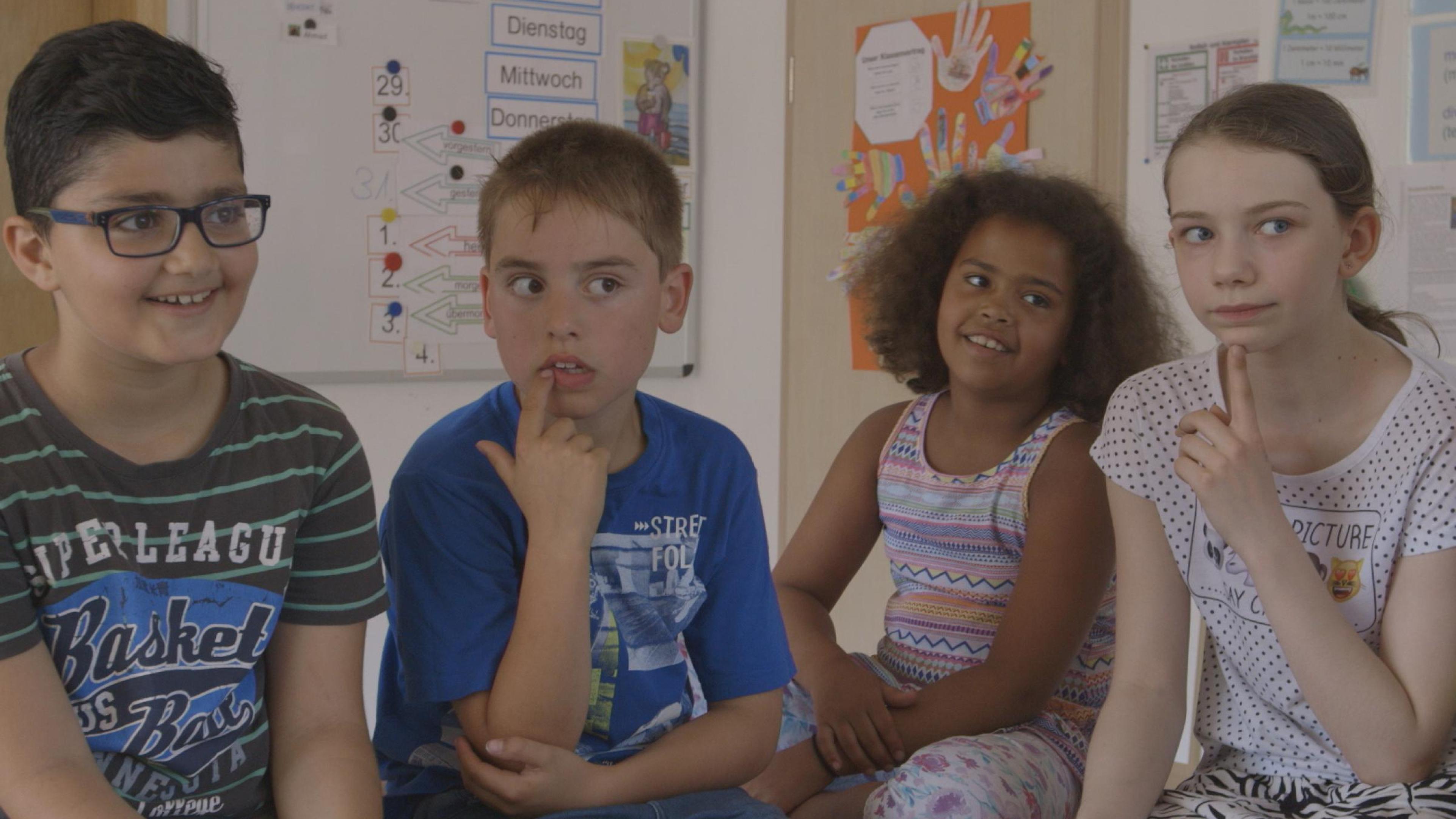 Vier Kinder sitzen zusammen in einem Klassenraum.