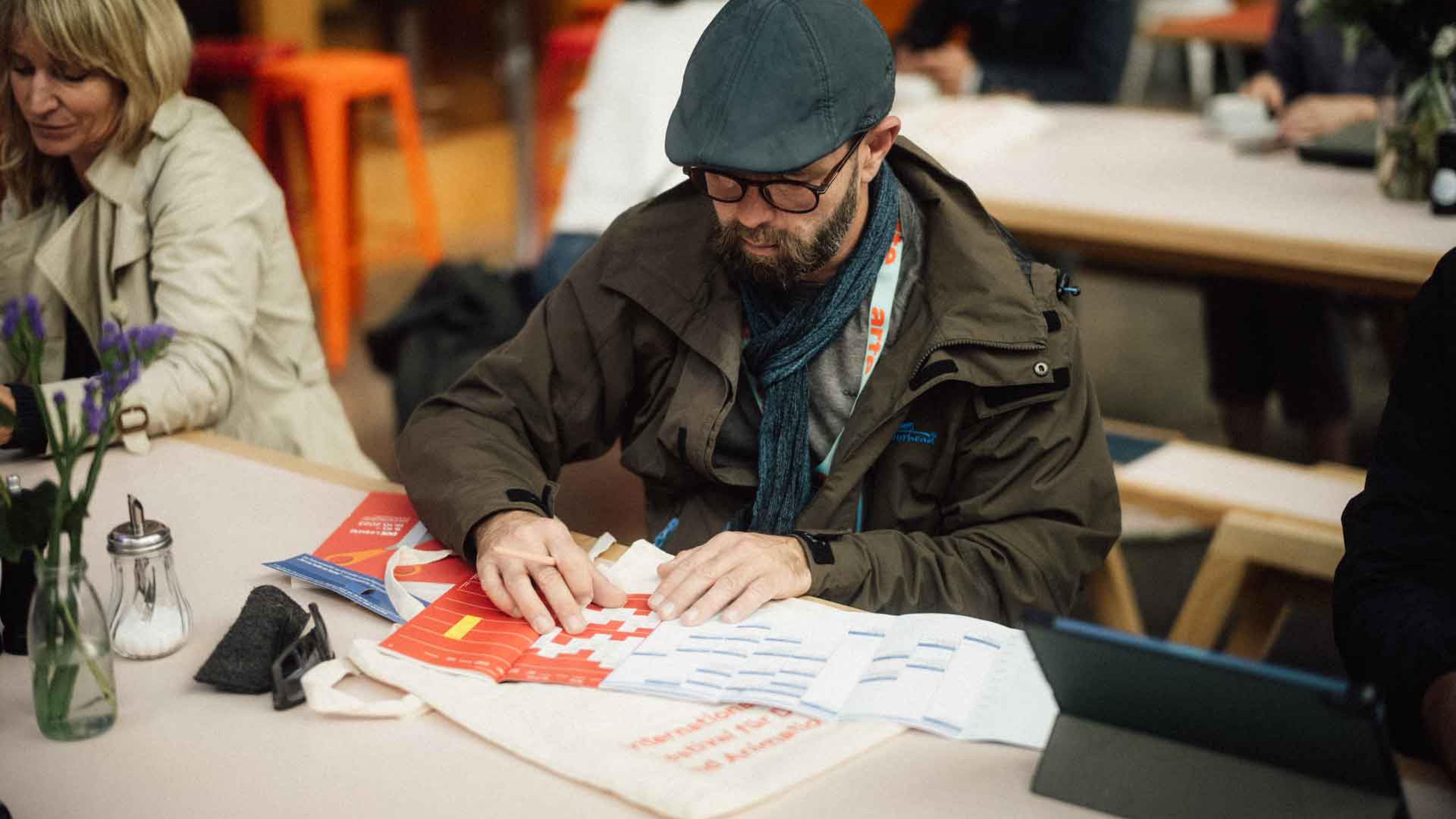 A man is coordinating his timetables by comparing a film programme and an industry schedule 