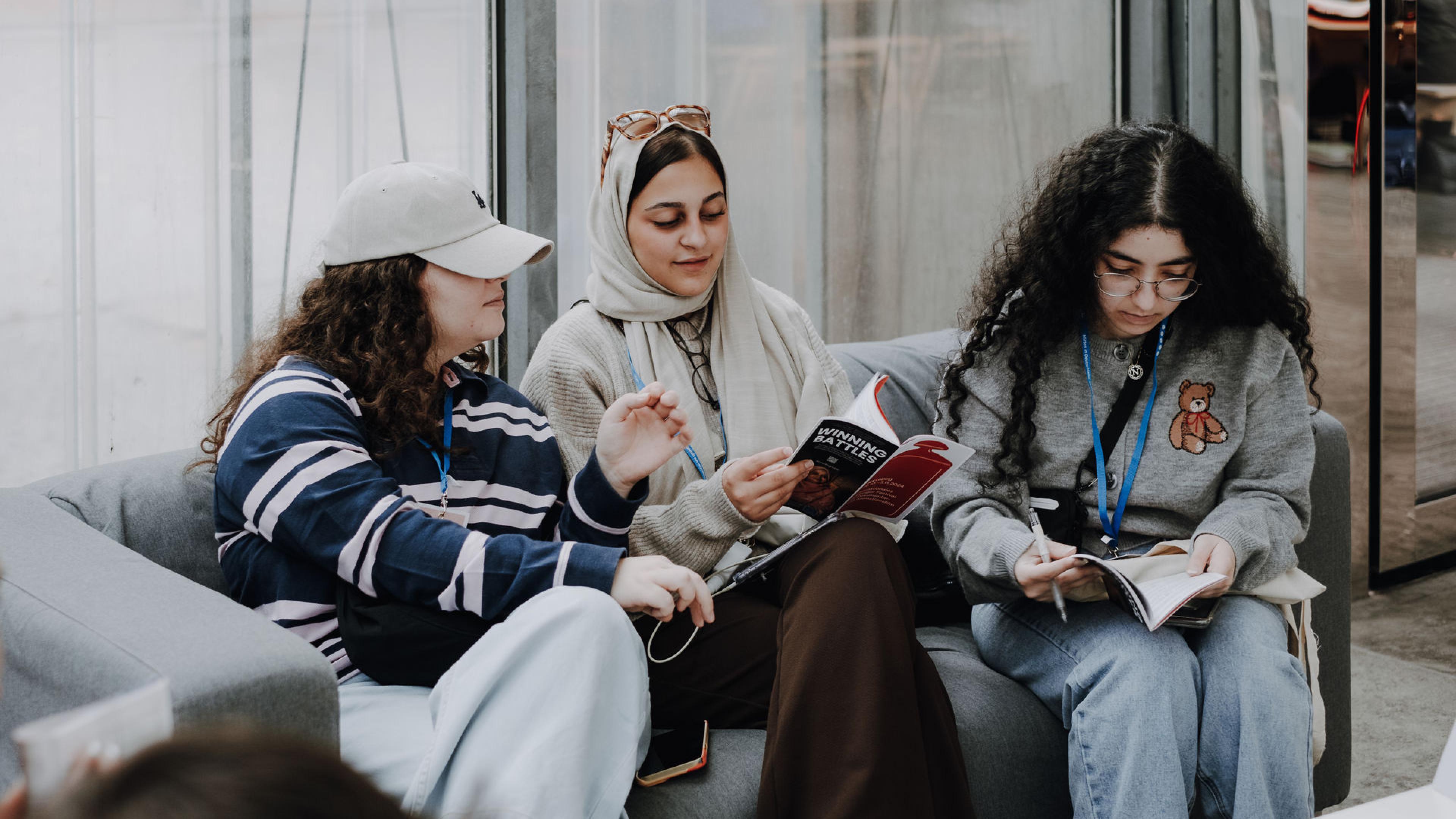 Drei Menschen sitzen auf einer Couch und lesen den Industry Guide