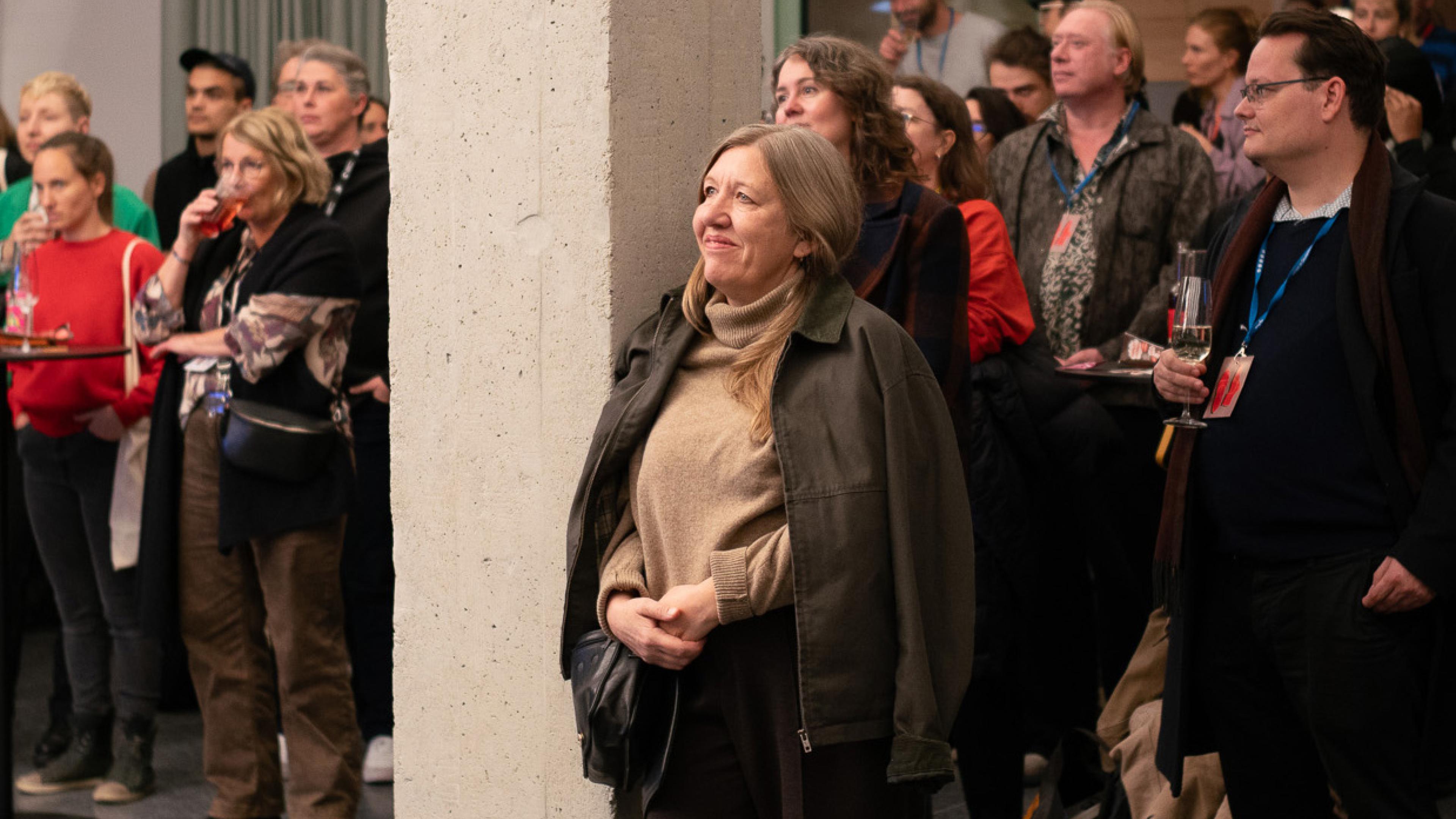 Nadja Tennstedt steht zufrieden an eine Säule gelehnt, hinter ihr ist eine Menschenmenge und sie schaut glücklich Richtung Bühne
