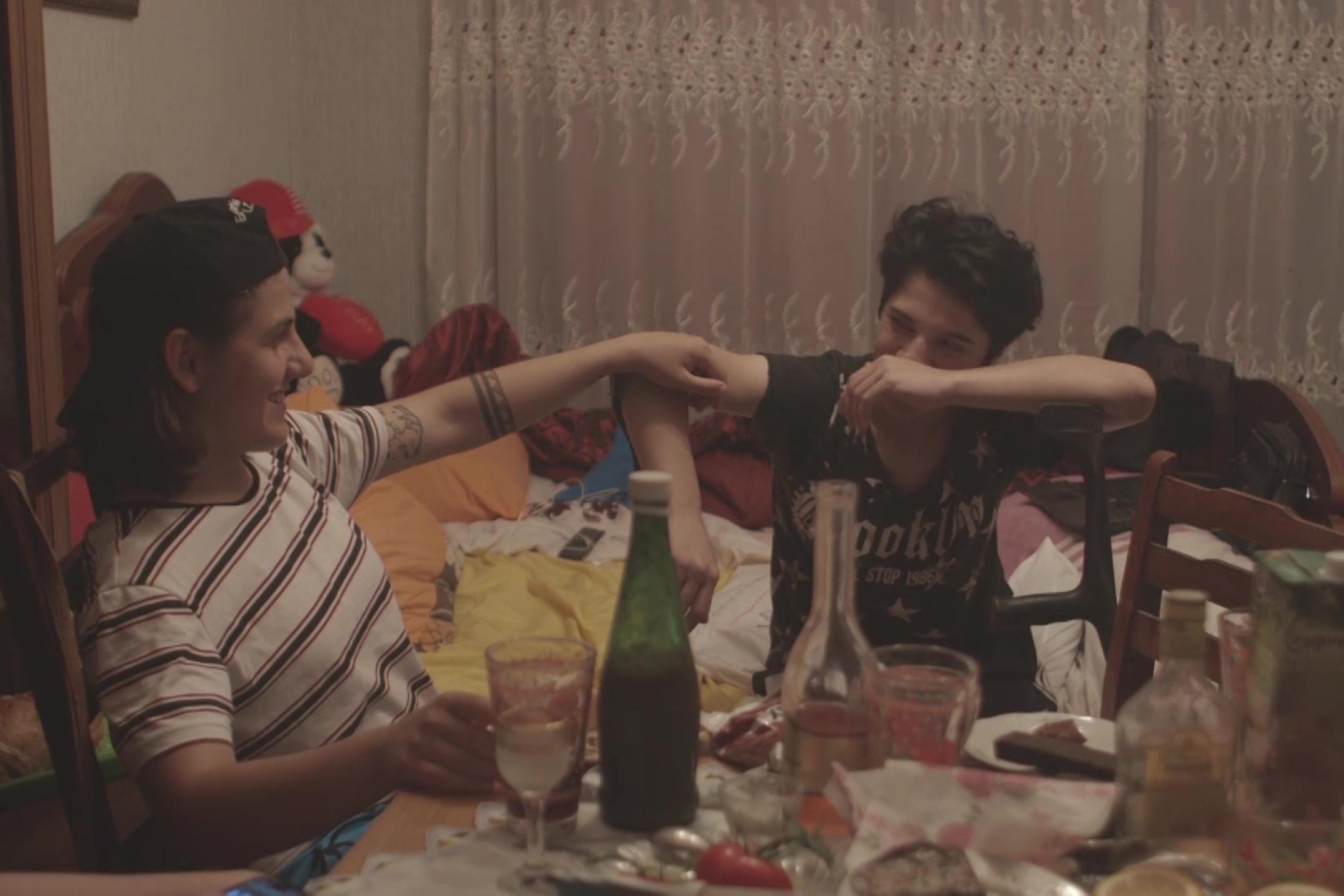 Two young persons sit at a table full of glasses and bottles
