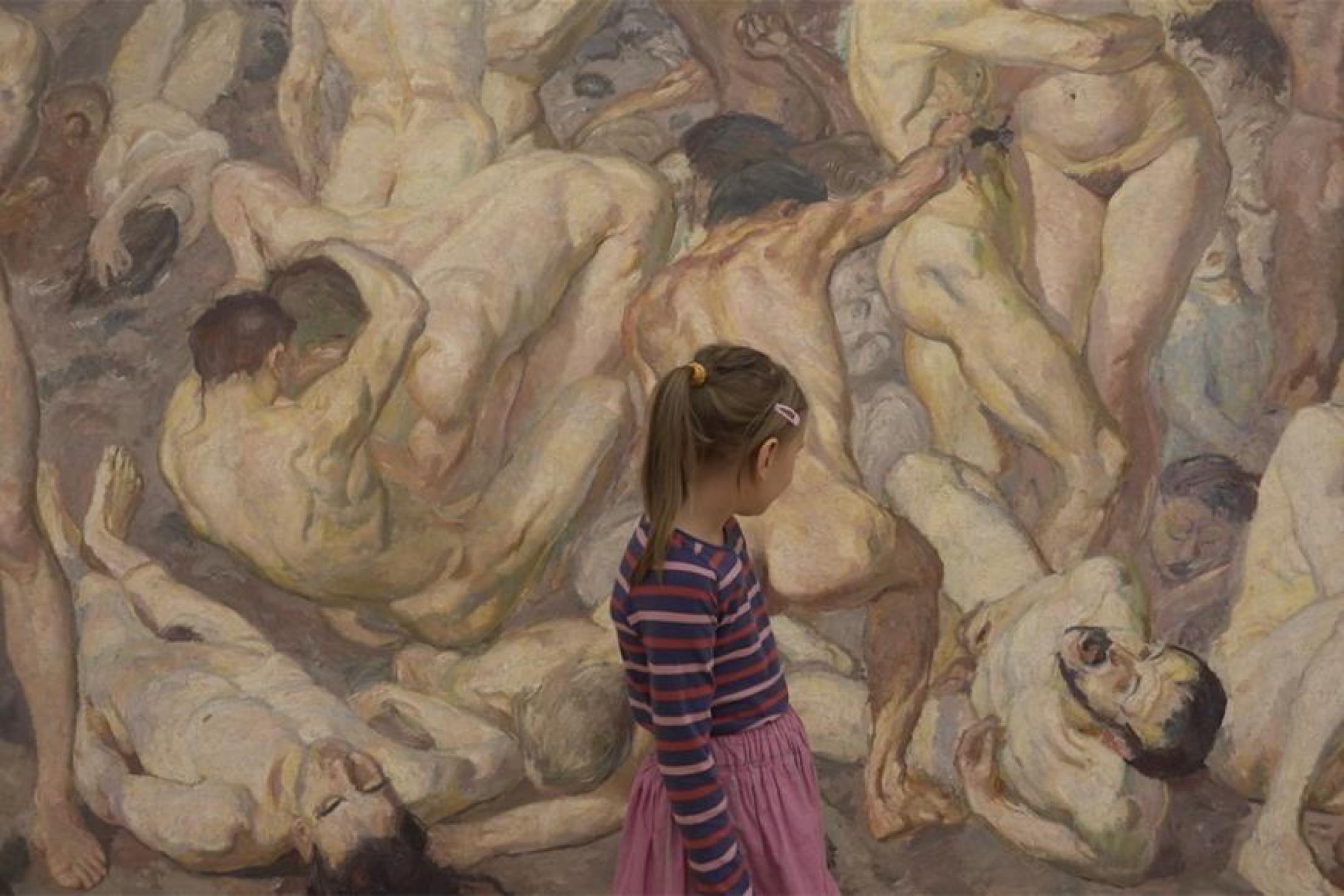 Ein junges Mädchen in geringeltem Pulli und Rock steht vor einem riesigen Gemälde, das viele nackte, verschlungene Menschen zeigt