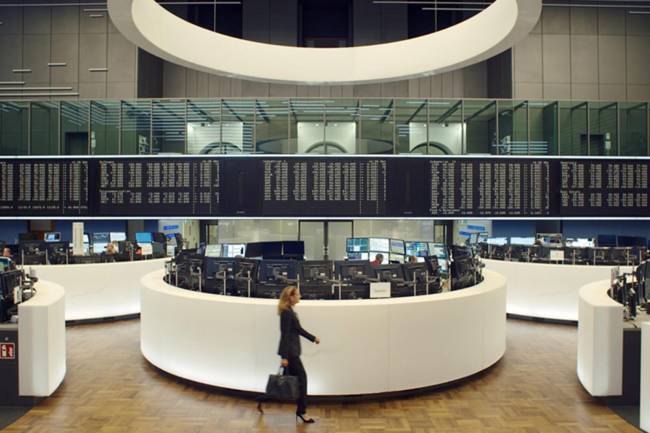 A woman in a business suit walk through the almost empty hall of a stock exchange.