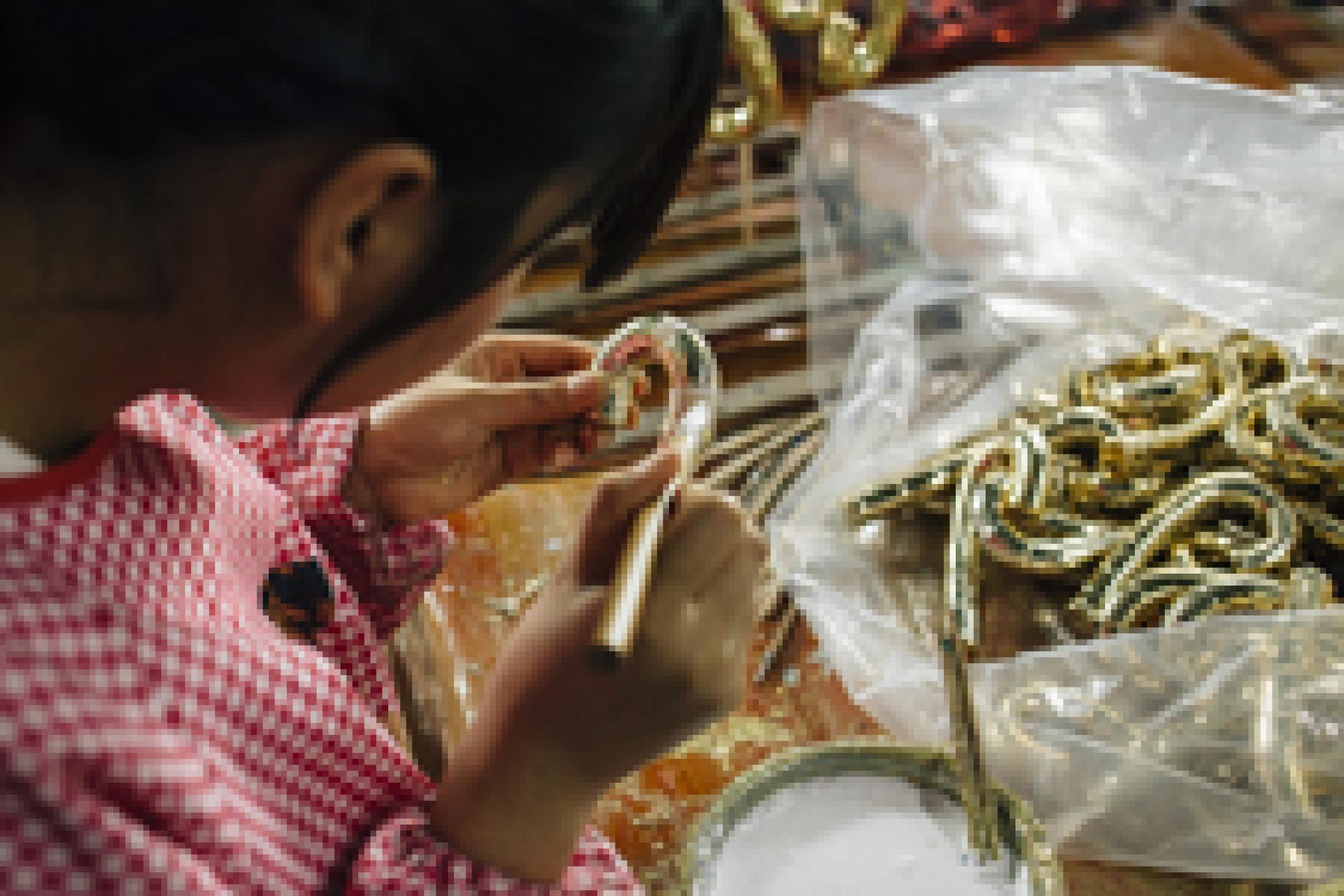 A person is bowing her head to work on some shiny Christmas decoration.