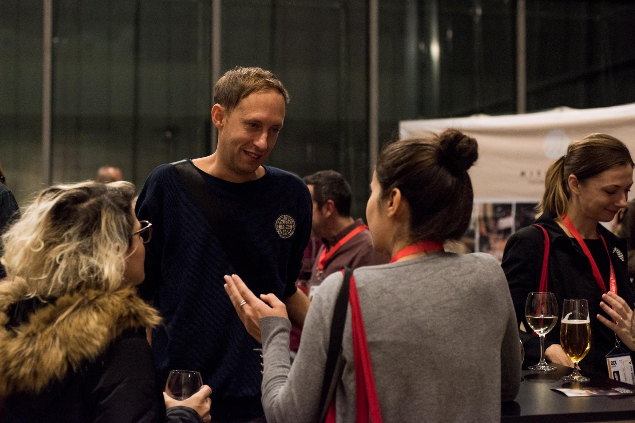 An evening event at the festival center at MdbK Leipzig: Selection Committee member Daniel Abma is talking to two women. 