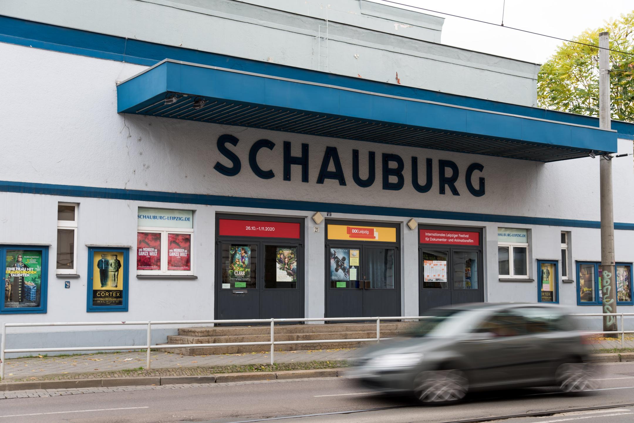 Eingang zu einem Kinogebäude mit blauem Flachdach. Über den Eingangstüren steht in großen Buchstaben "Schauburg".