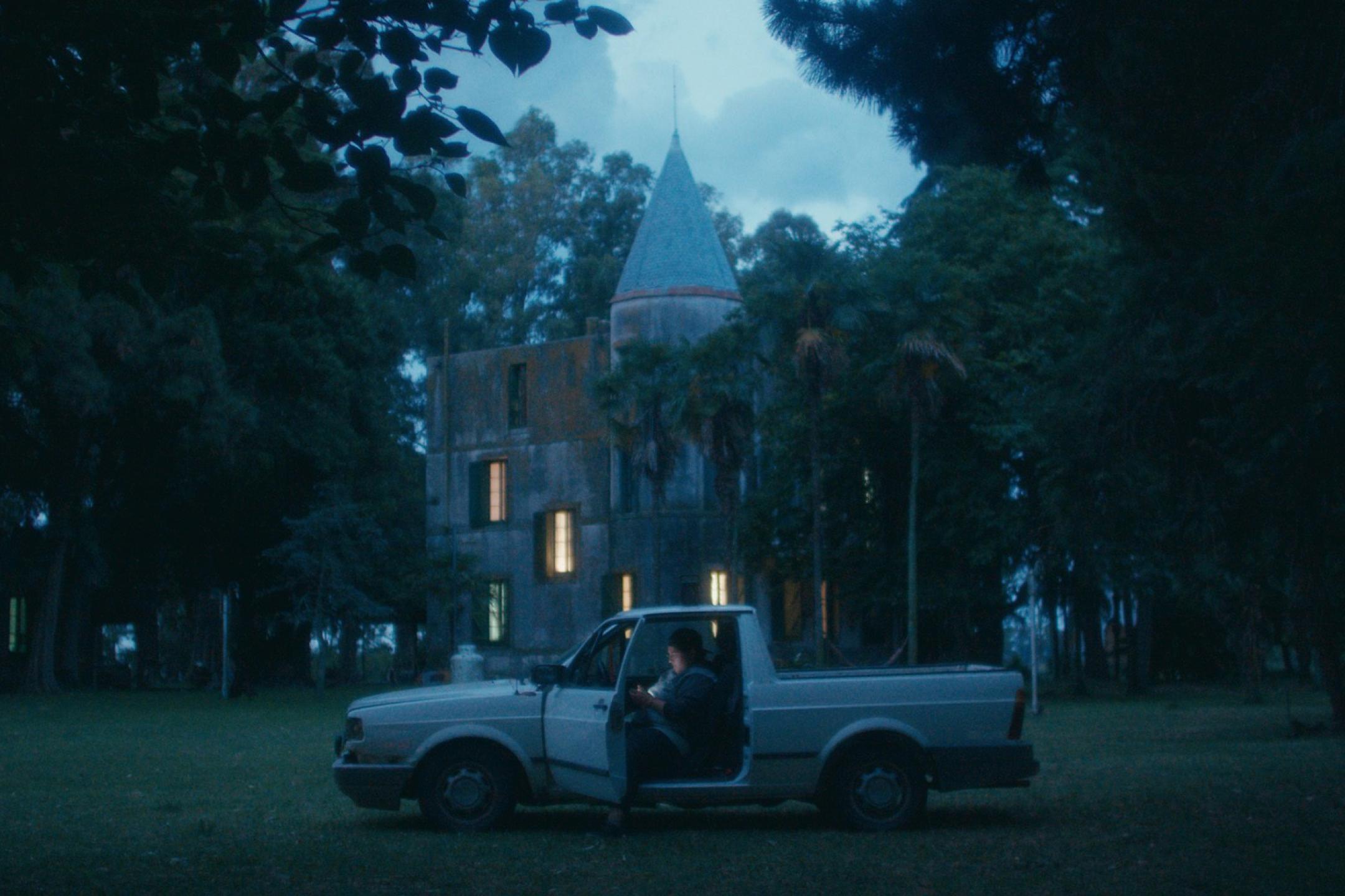 A pick up truck parks on a lawn in front of a castle. 