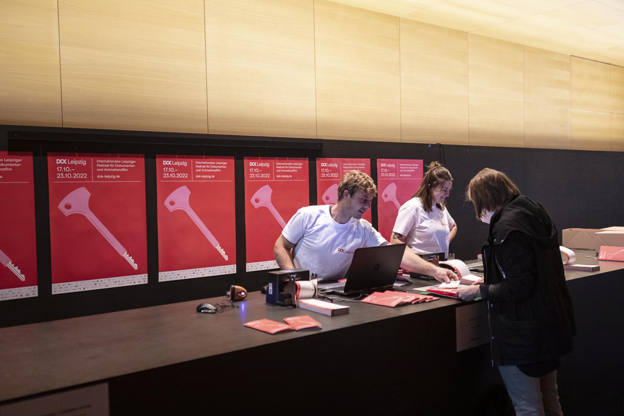 An einer Ticketkasse beraten zwei Dok-Mitarbeiterinnen eine Festivalbesucherin