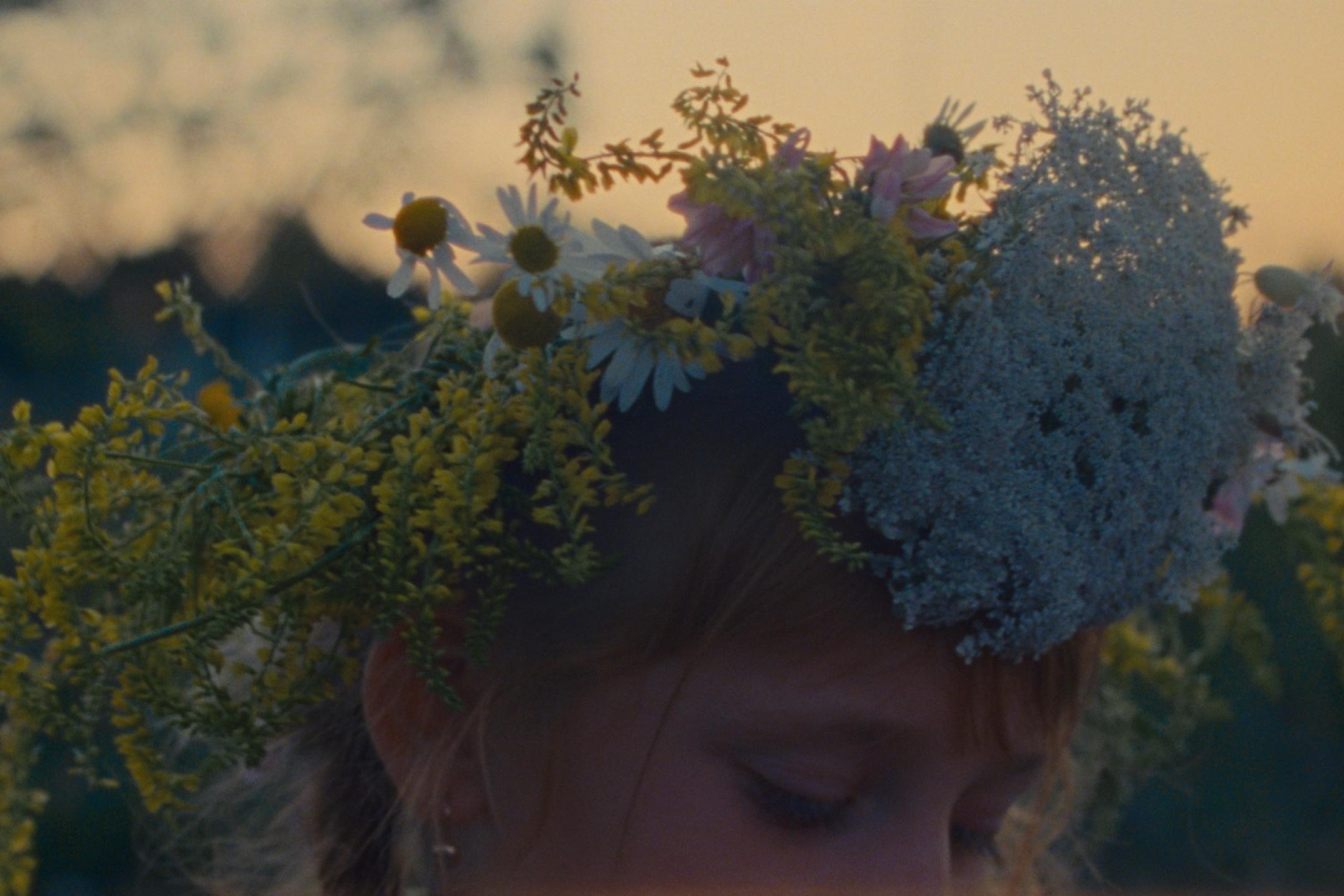 Kopf eines Mädchens mit einem Kranz aus Wiesenblumen.