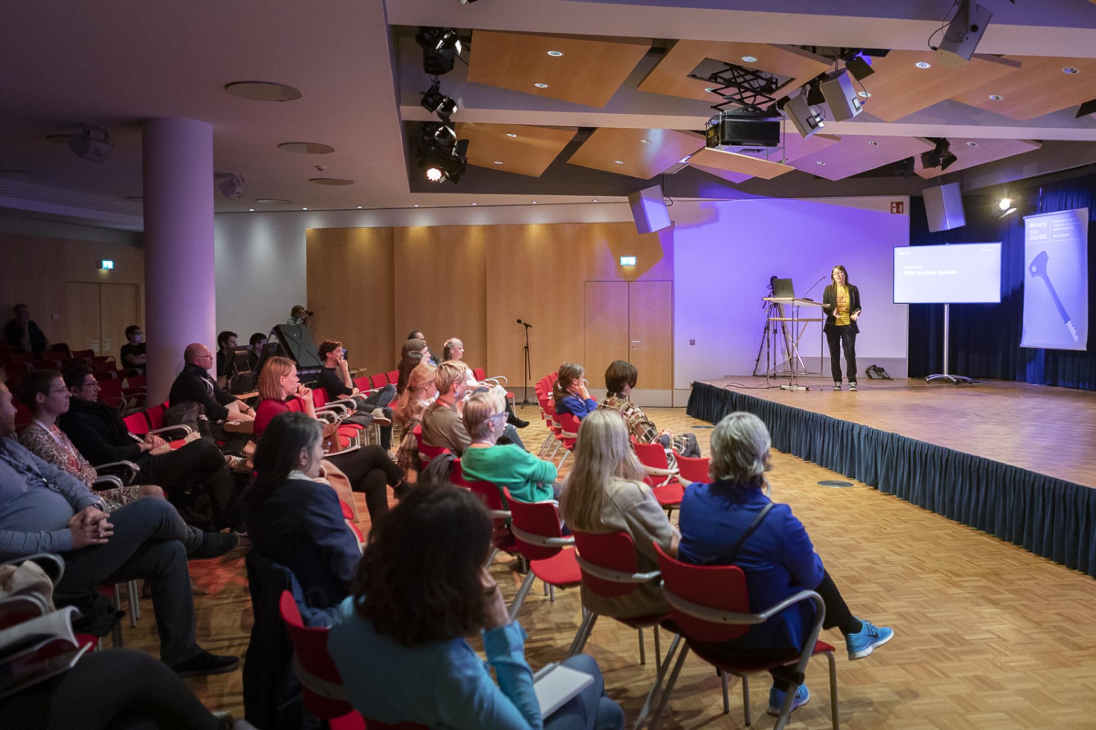 A person stands on a podium in front of an audience.