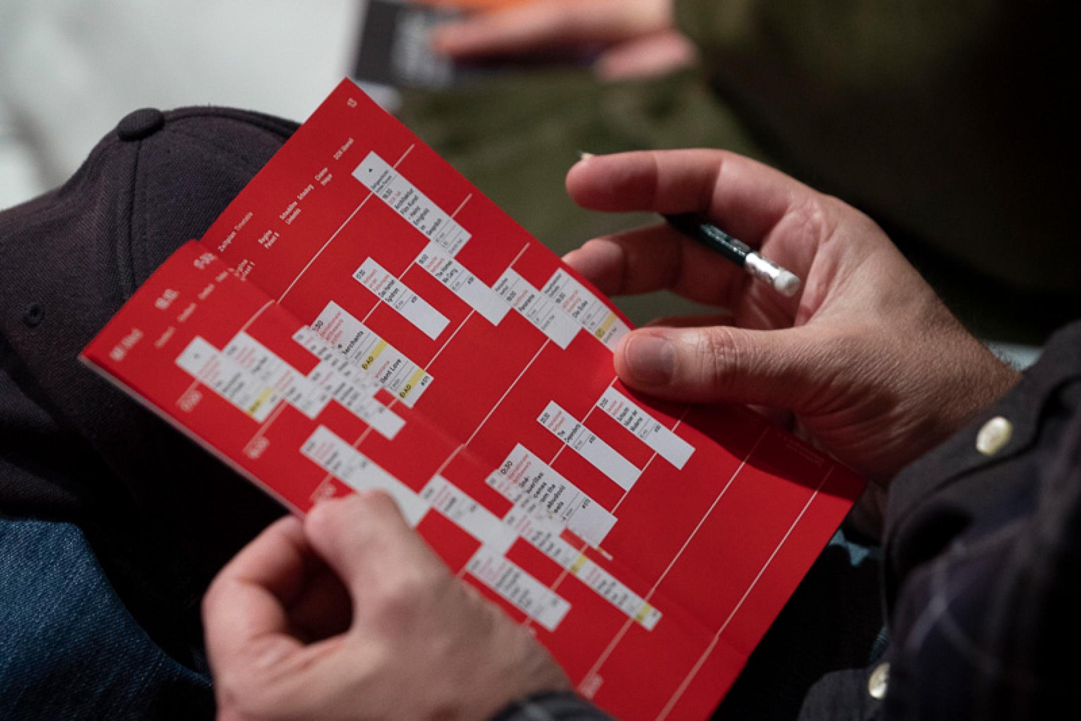 Close-up of two hands flipping through a programme booklet