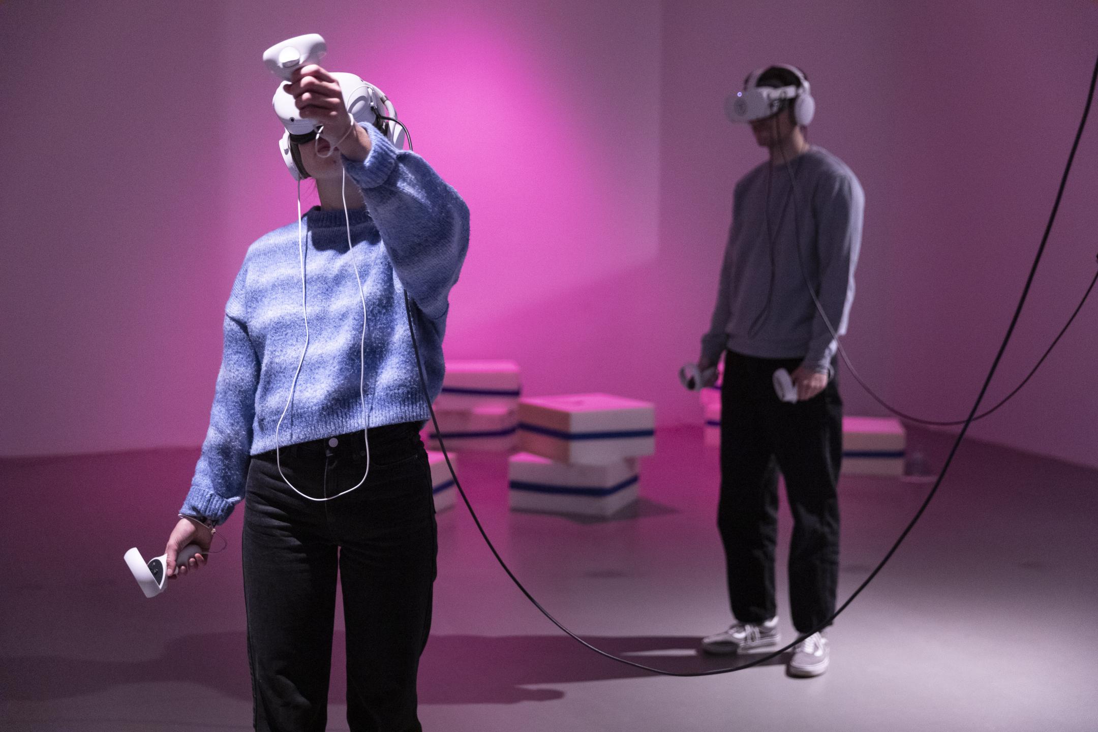 Zwei Personen mit VR-Brille stehen in einem fast leeren Raum.