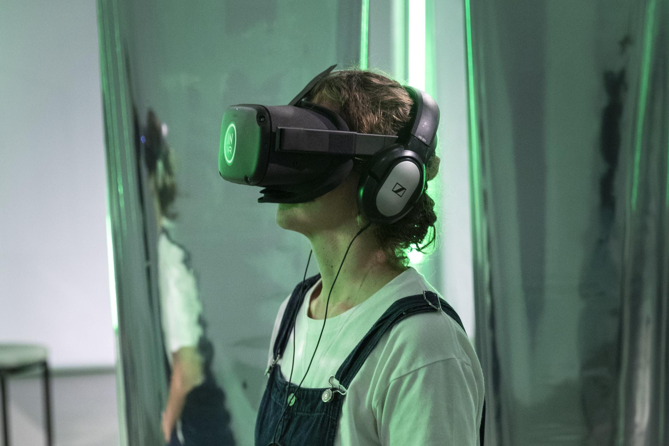 A person sits on a chair and wears a VR head set.