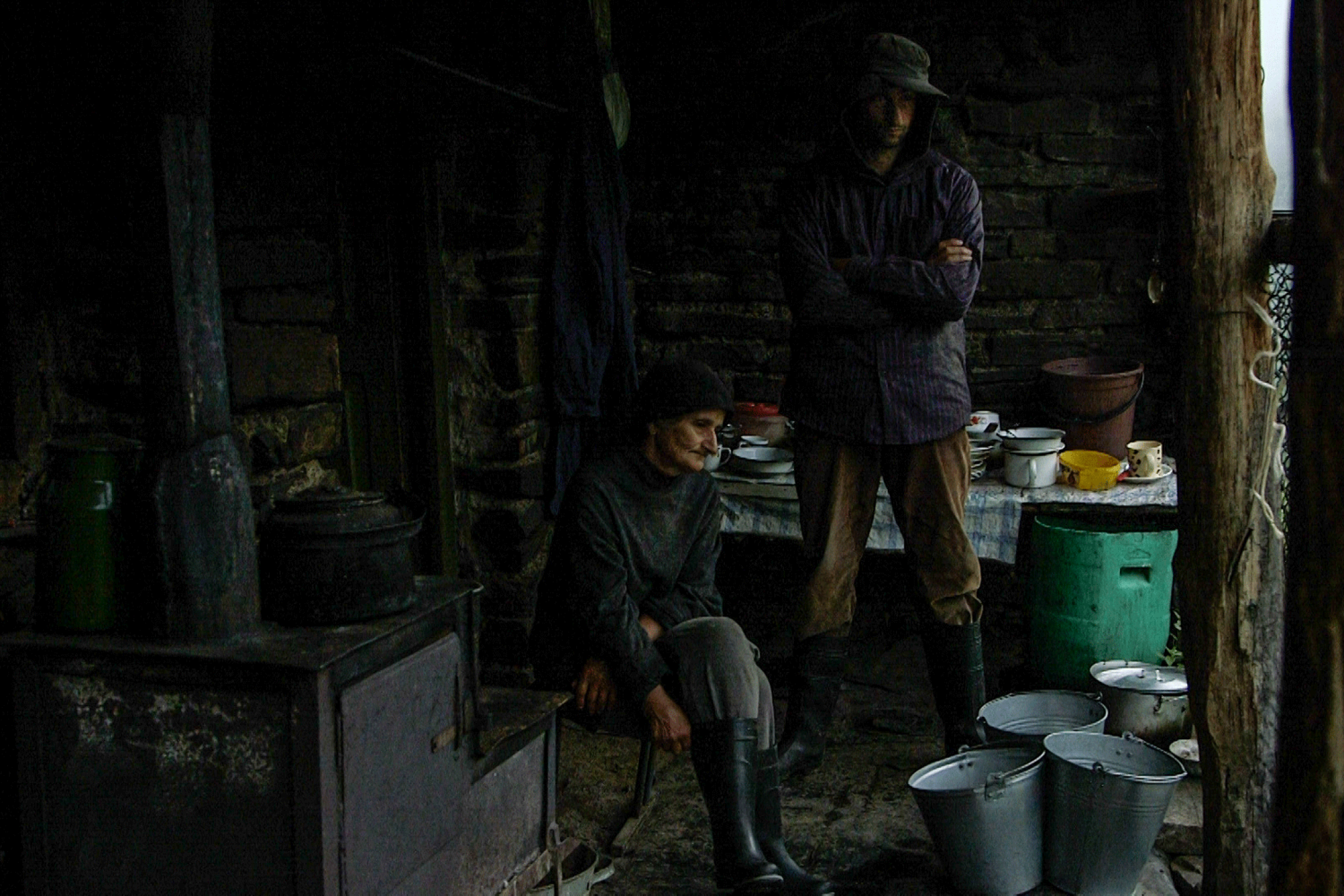 A man and an elderly woman in between stacks of buckets and bowls.