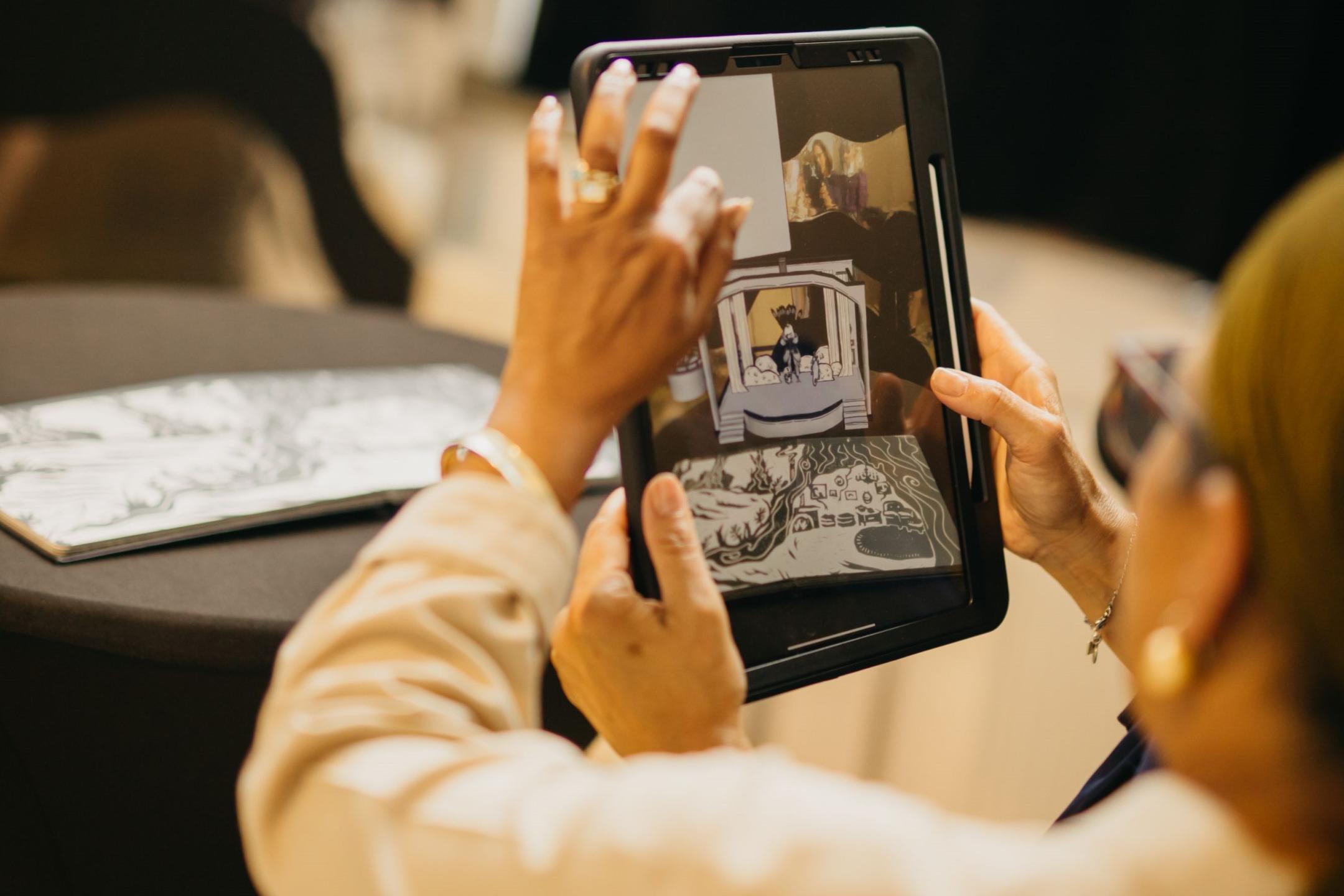 Someone ist holding an iPad and another person is dragging a picture over the screen with their finger