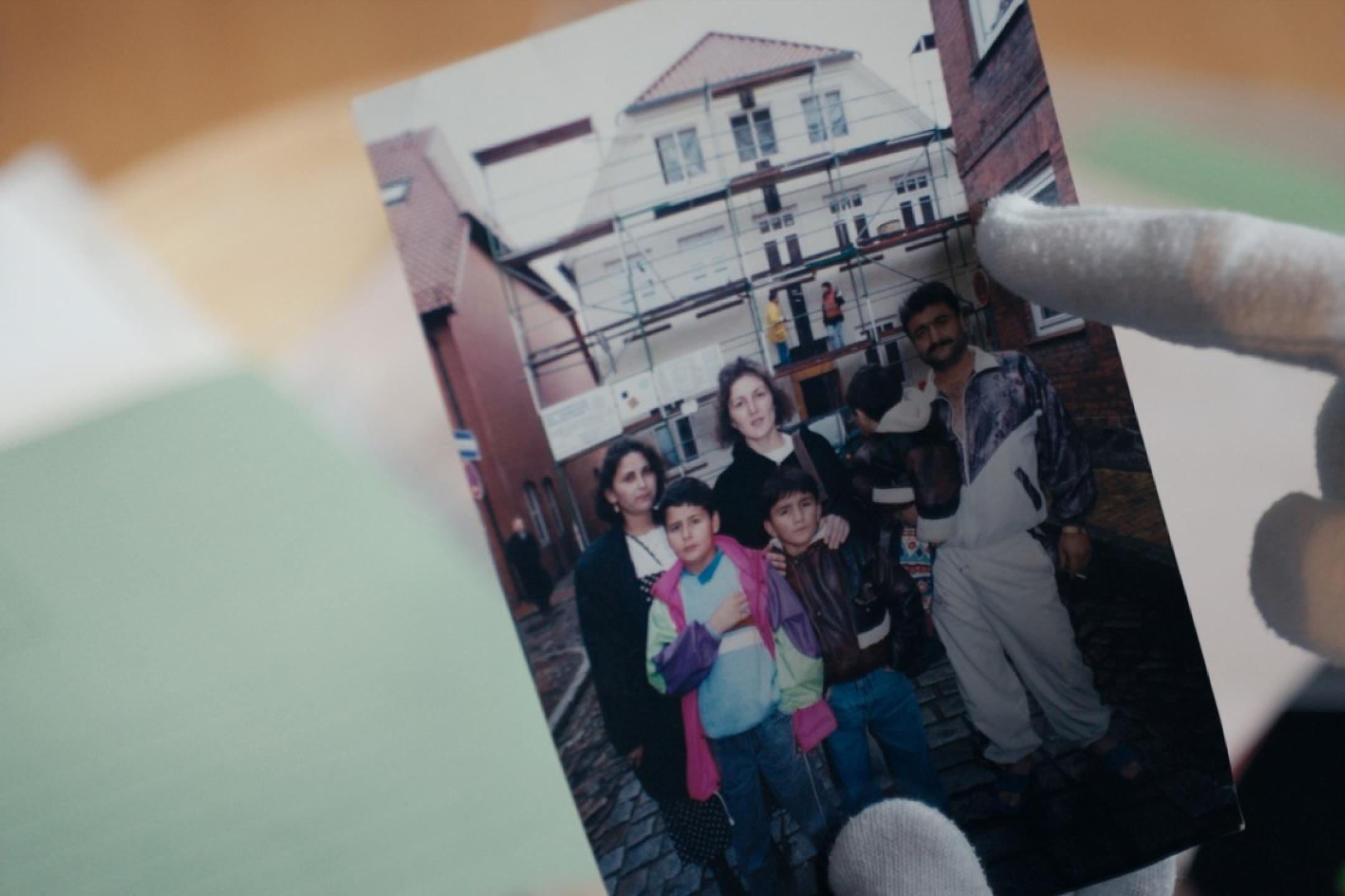 A family picture of three adults and three children held by gloved hands