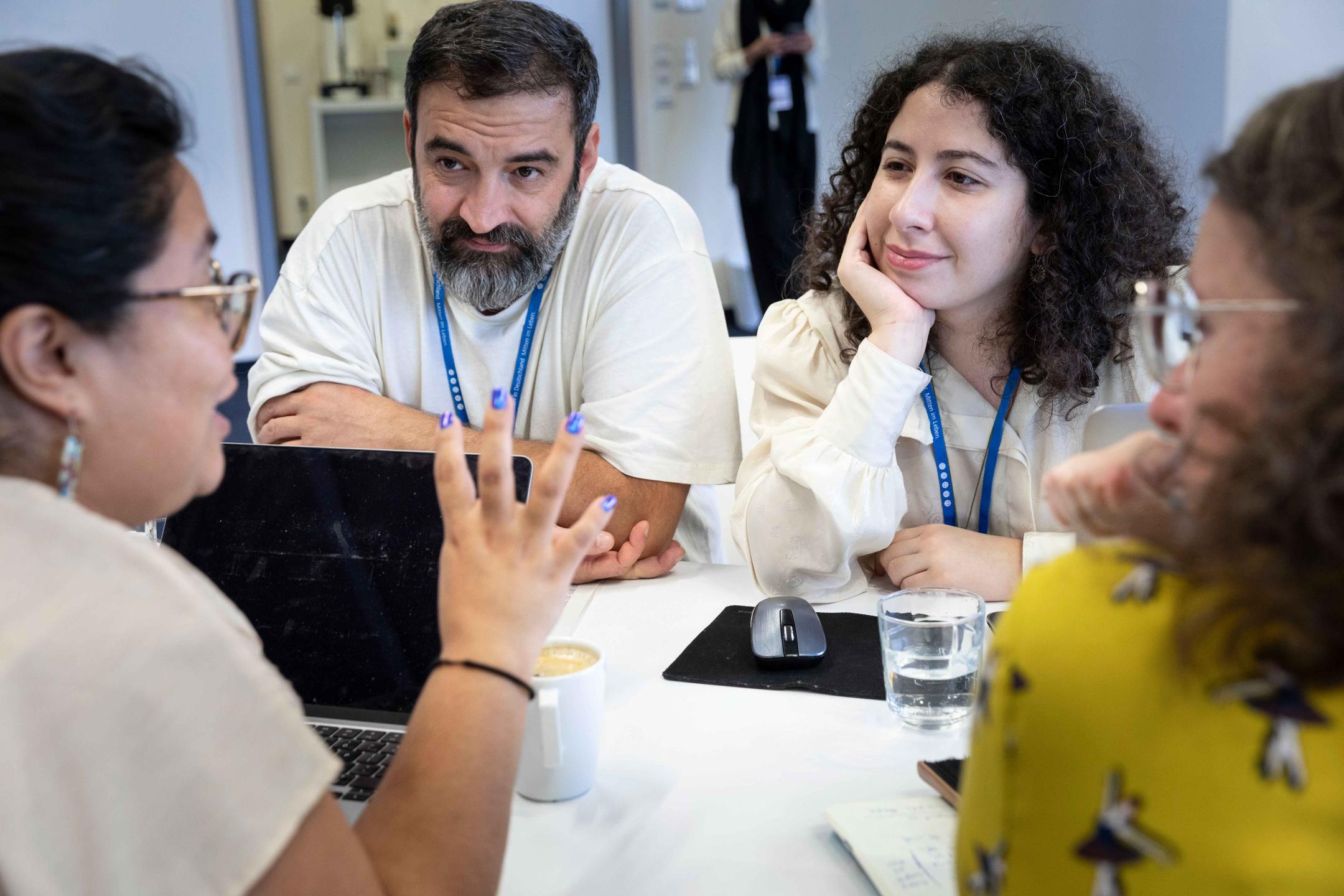 Two people listen very intently to the two sitting opposite them at a table