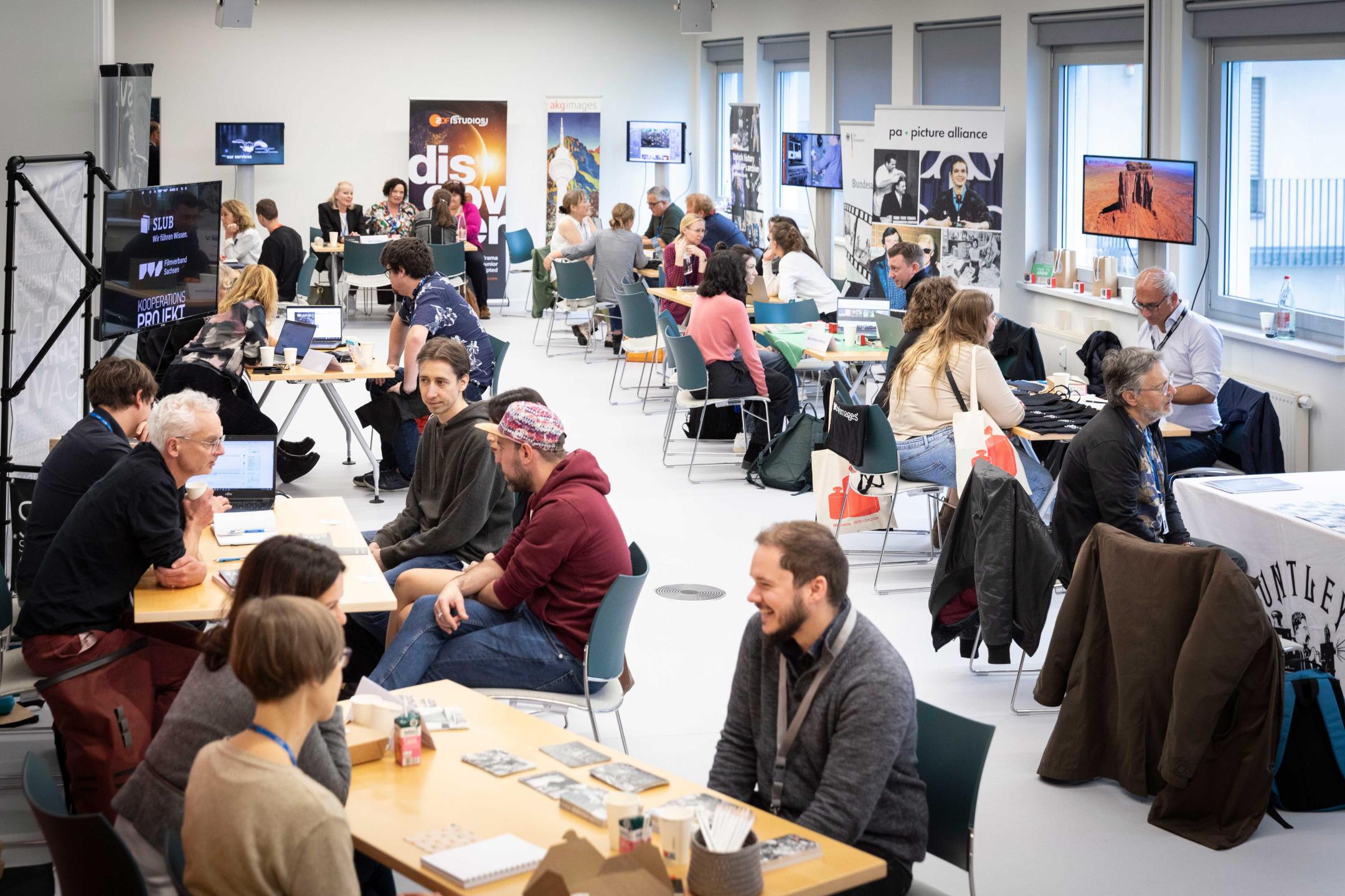 A room full of people all sitting at tables in small groups to discuss archives