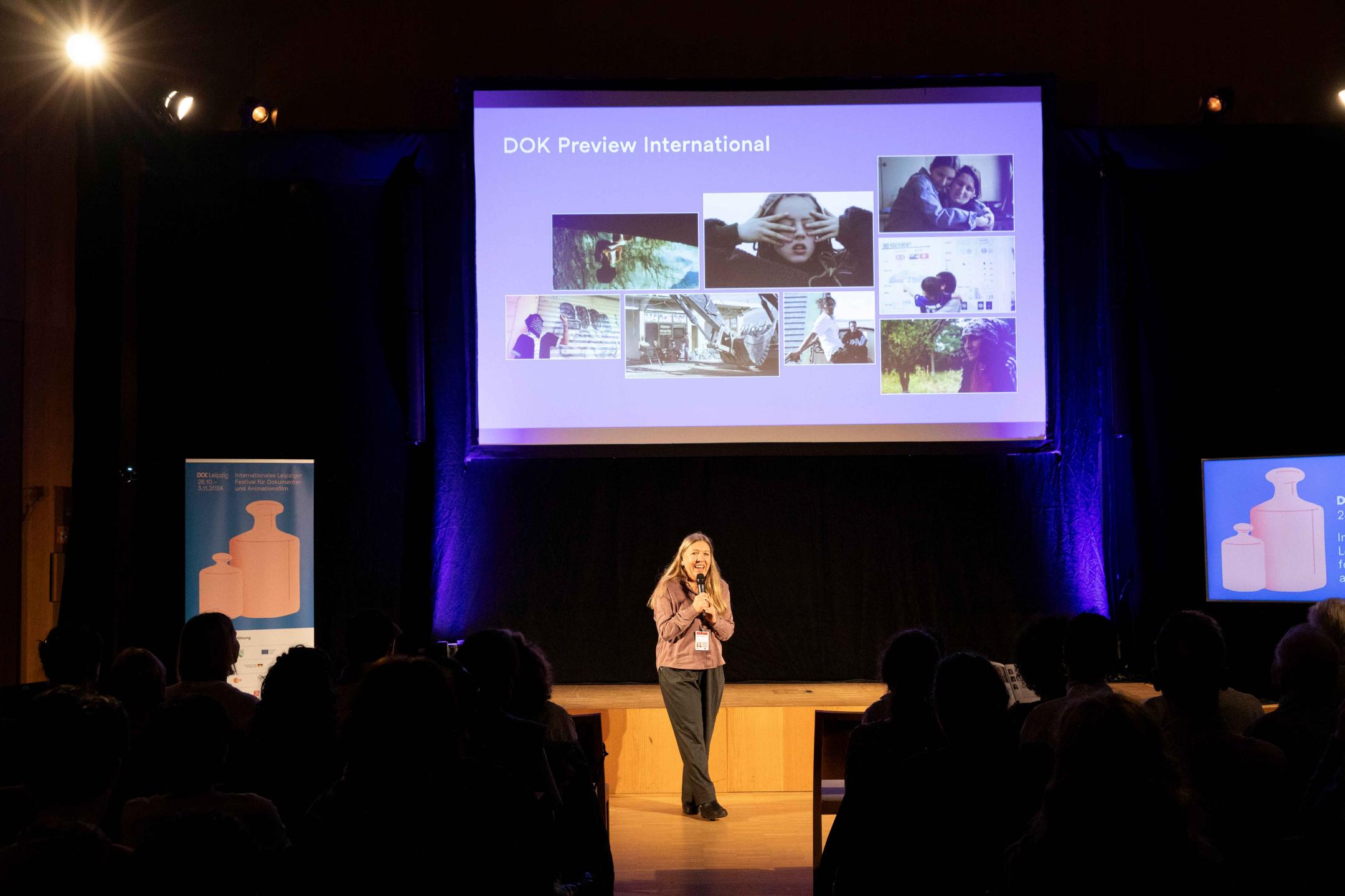 Nadja Tennstedt is announcing the start of Dok Preview International Presentation in front of an audience