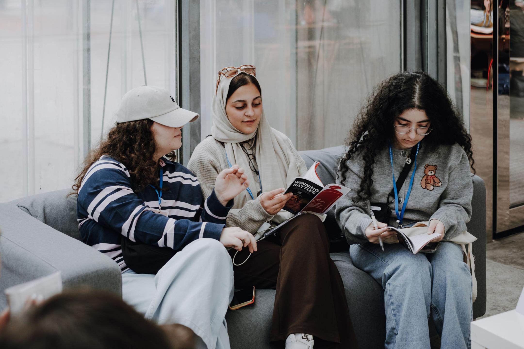 Drei Menschen sitzen auf einer Couch und lesen den Industry Guide