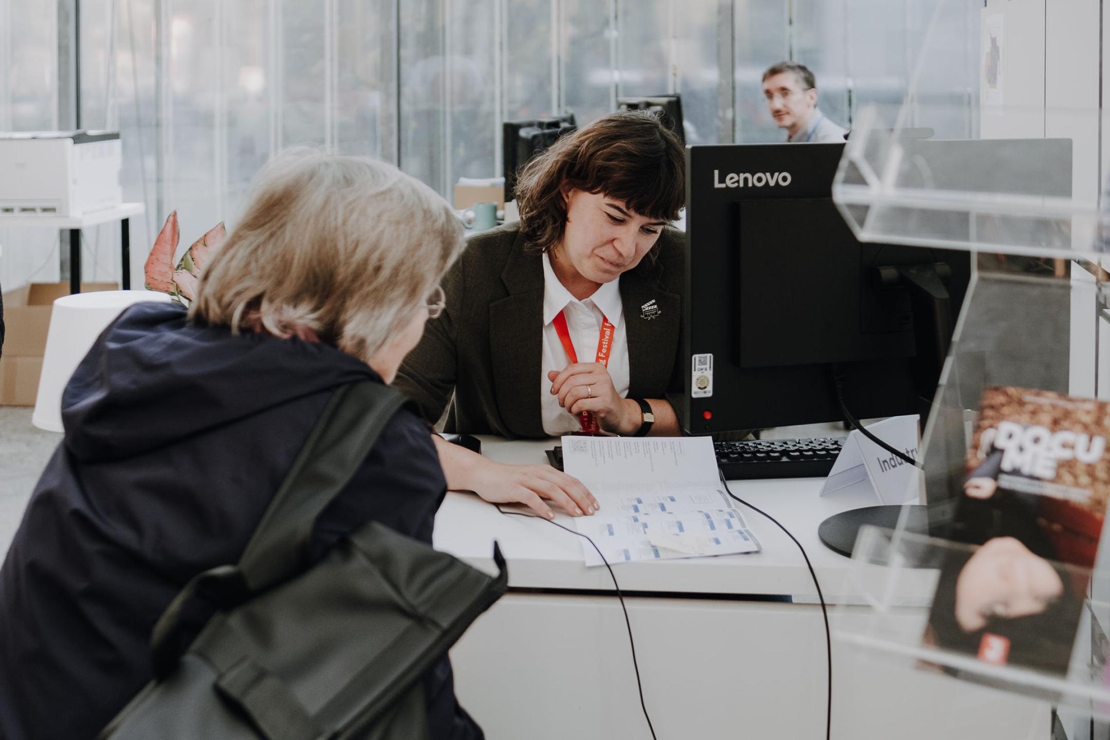Eine Persson hilft einer anderen am DOK Industry desk und zeigt den Guide