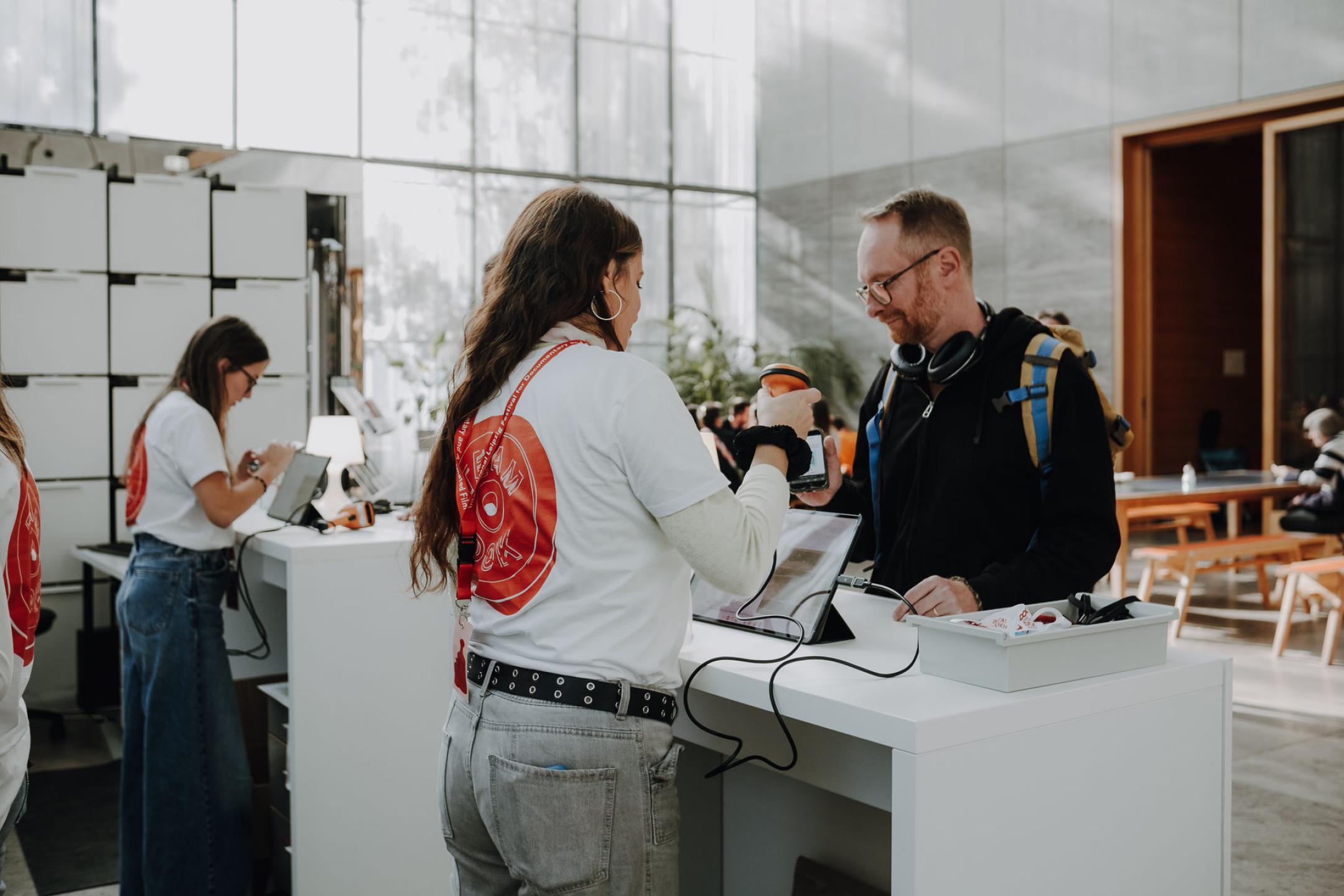 Eine Person scannt den Akkreditierten-Pass einer anderen Person ab