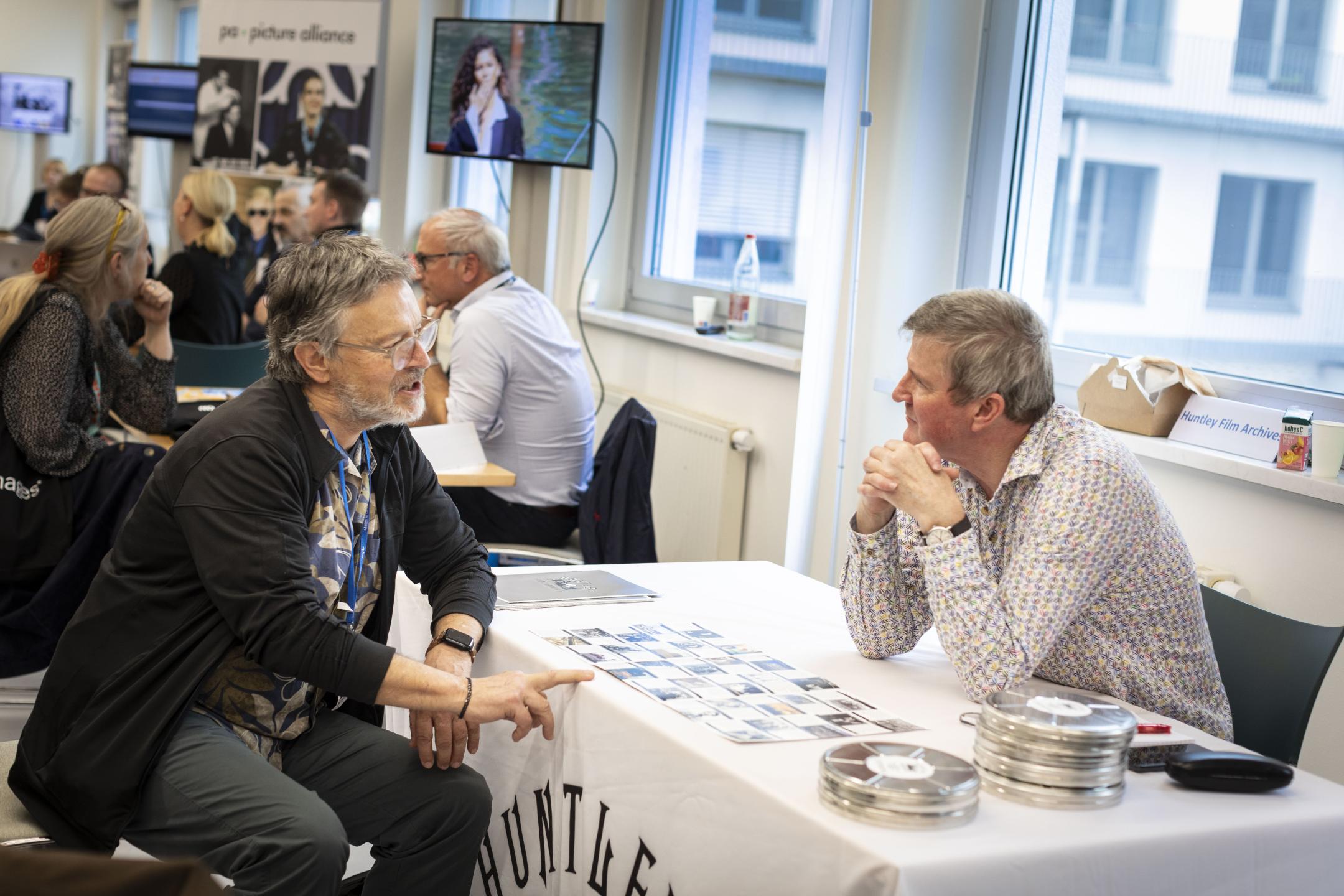 photograph of two men sitting opposite each other at a table talking