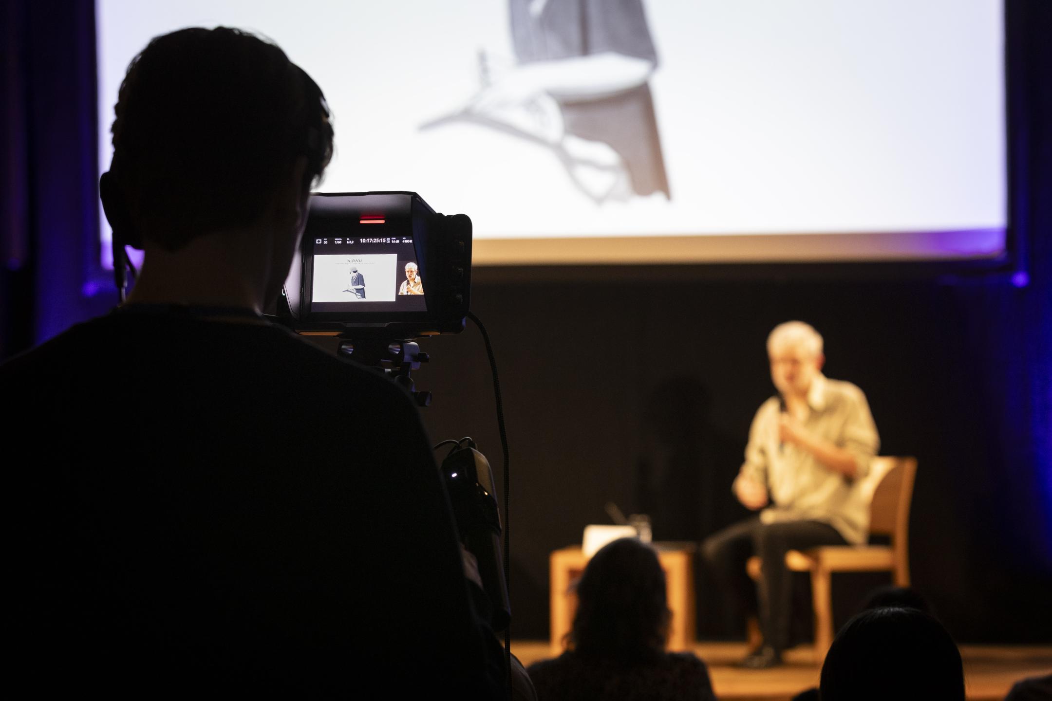 Nahaufnahme eines Kameradisplays, die eine Person auf einer Bühne filmt