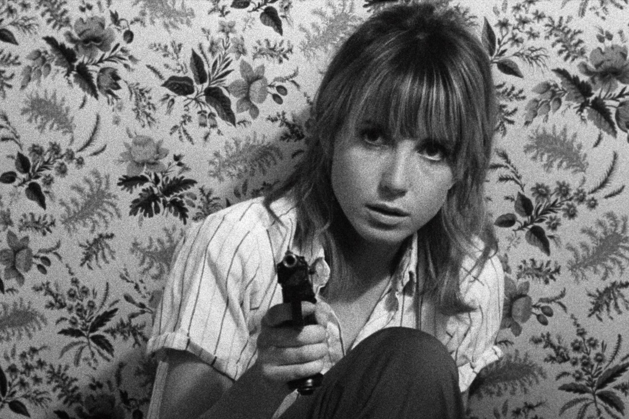 schwarz weiß bild einer frau, die eine pistole richtung kamera hält