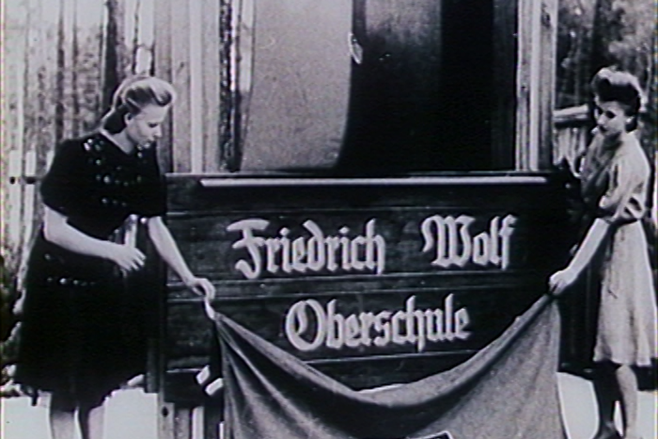 Zwei FDJ-Mädchen enthüllen das Banner der "Friedrich Wolf Oberschule"