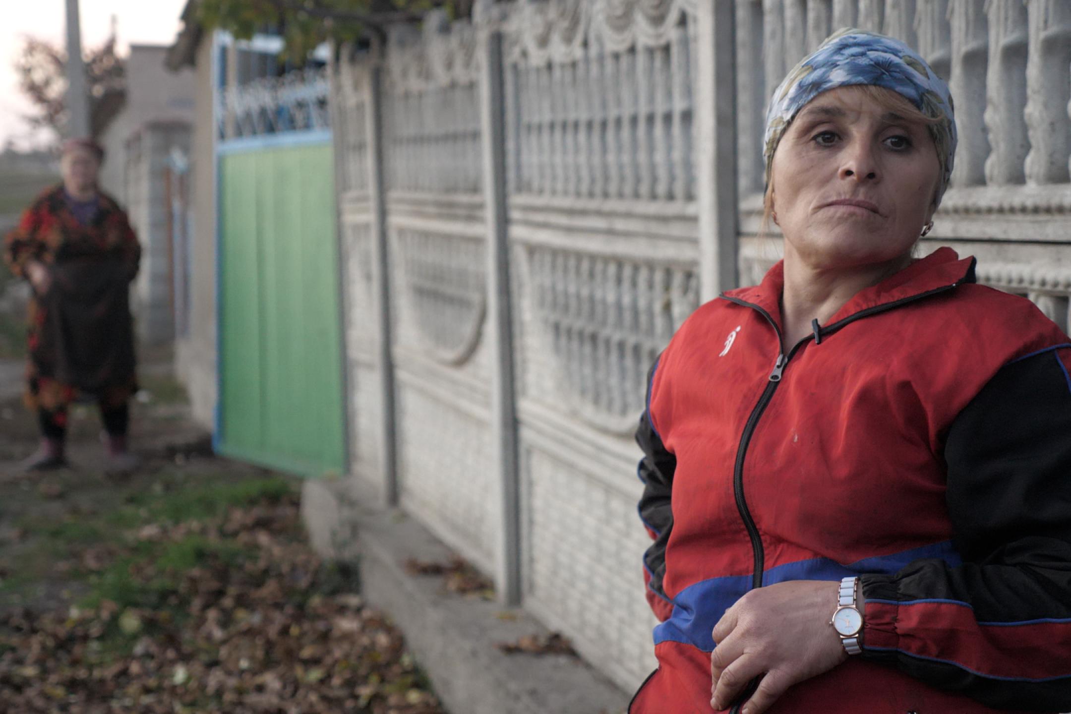 Filmstill "Electing Ms. Santa", ältere Frau mit Kopftuch lehnt an Zahn