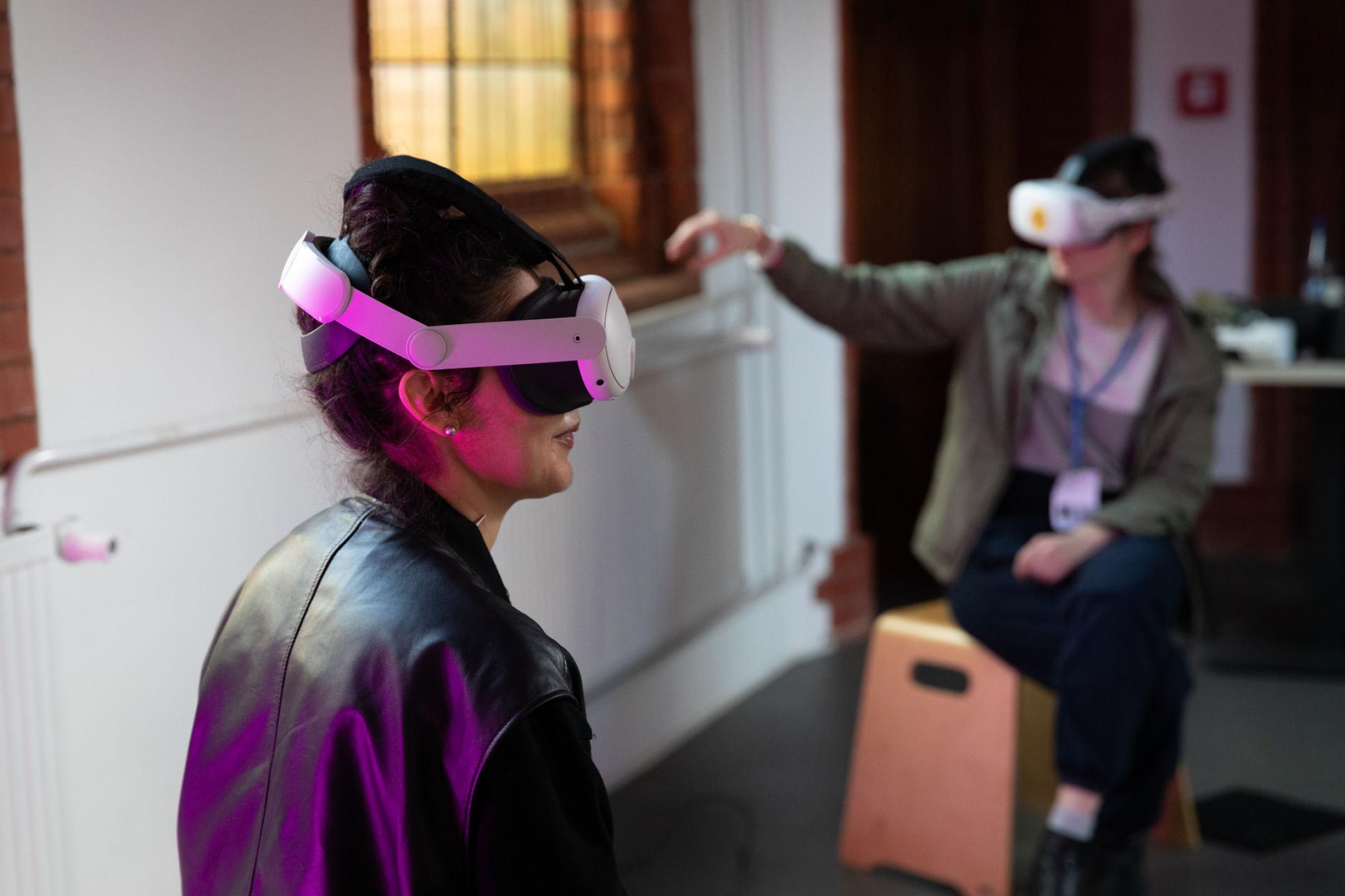 Verteilt in einem Raum schauen zwei Personen XR Filme durch VR-Brillen