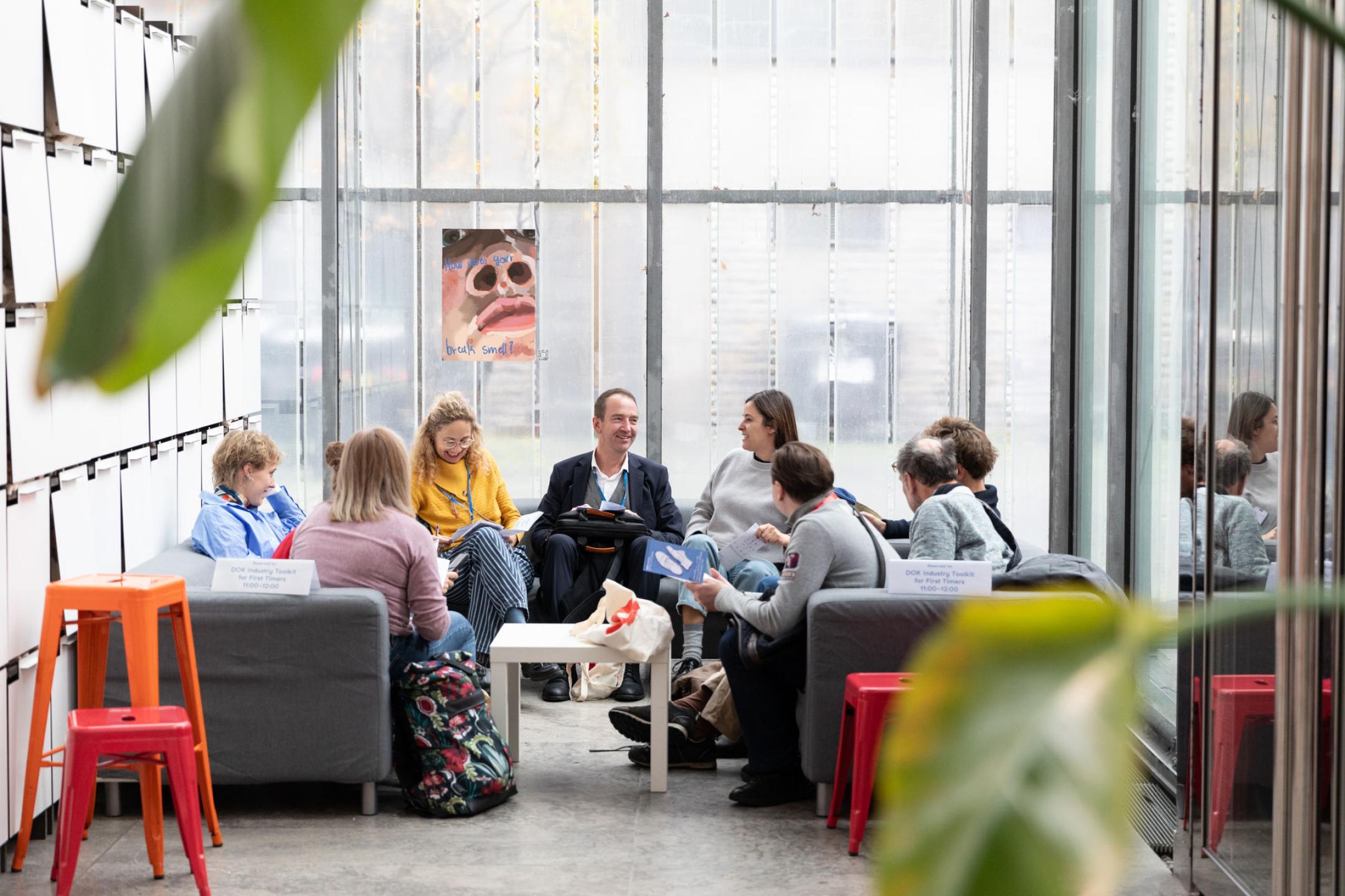 Eine Gruppe sitz sich auf zwei Sofas in einer lockeren Runde gegenüber und unterhalten sich.