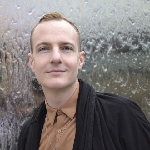 Portrait of Rob Eagle looking at the camera, with short hair and a piercing in one ear