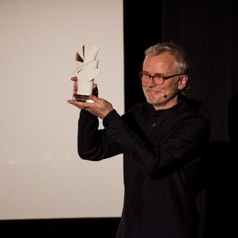 Festivalleiter Christoph Terhechte hält die Preisstatue einer Goldenen Taube hoch.