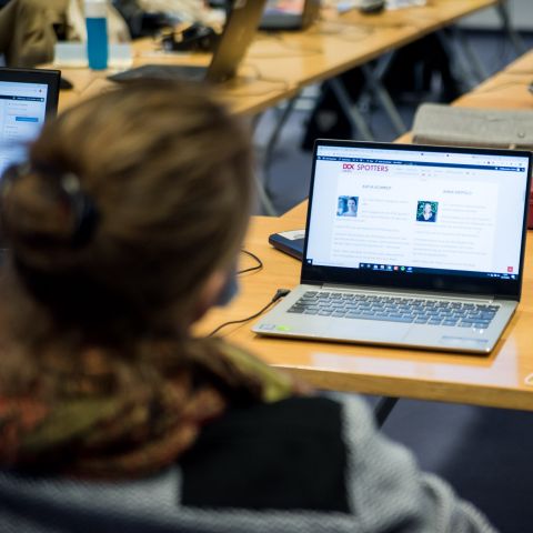 Blick über die Schulter einer Jugendlichen auf einen Laptop-Bildschirm mit dem DOK Spotters Blog.