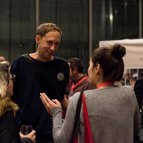 An evening event at the festival center at MdbK Leipzig: Selection Committee member Daniel Abma is talking to two women.