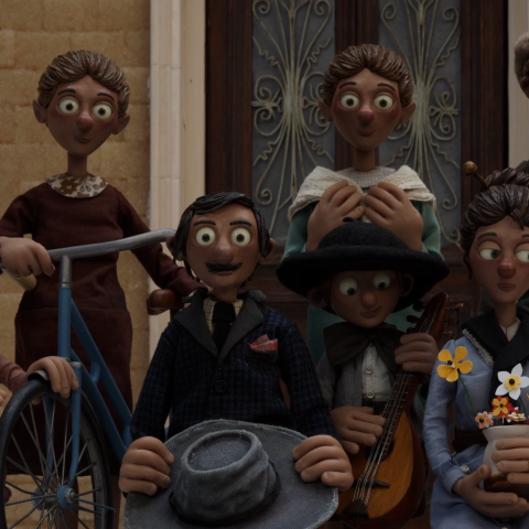 A family of clay figures posing in fashionable clothes for a family photo in front of their beige-coloured home, there are six adults and three children, some of them carry flowers and musical instruments in their hands.