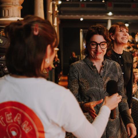 Volunteer reicht Speakerin ein Mikrofon 