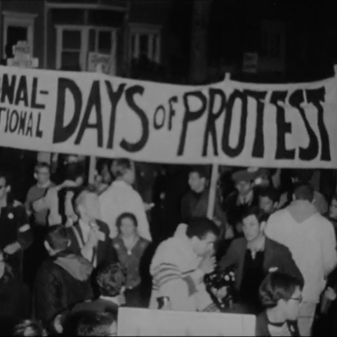schwar weiß fotografie von protestanten die ein banner hoch halten auf dem "National-International Days of Protests" steht
