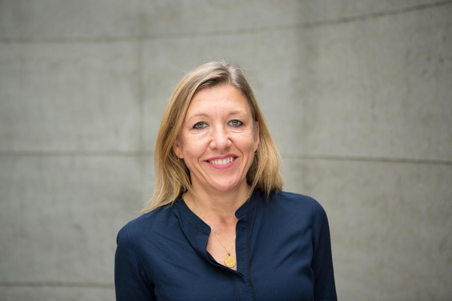 Portraitfoto von Nadja. Sie trägt eine dunkelblaue Bluse und lächelt in die Kamera.