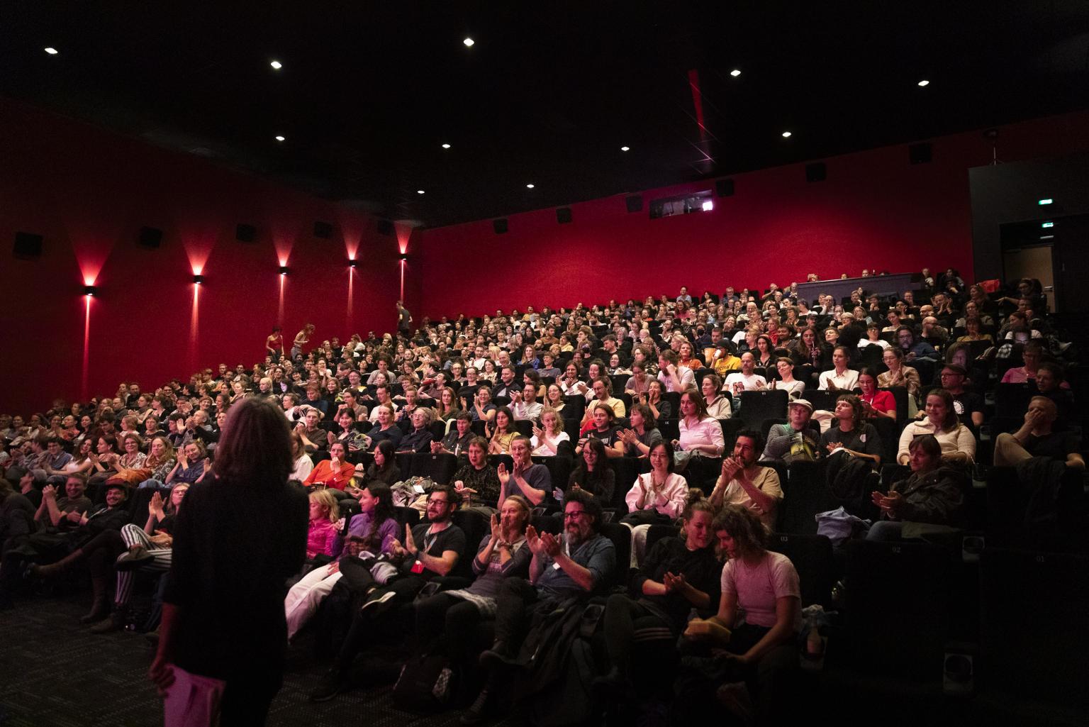 Audience give applause in a fully packed cinema