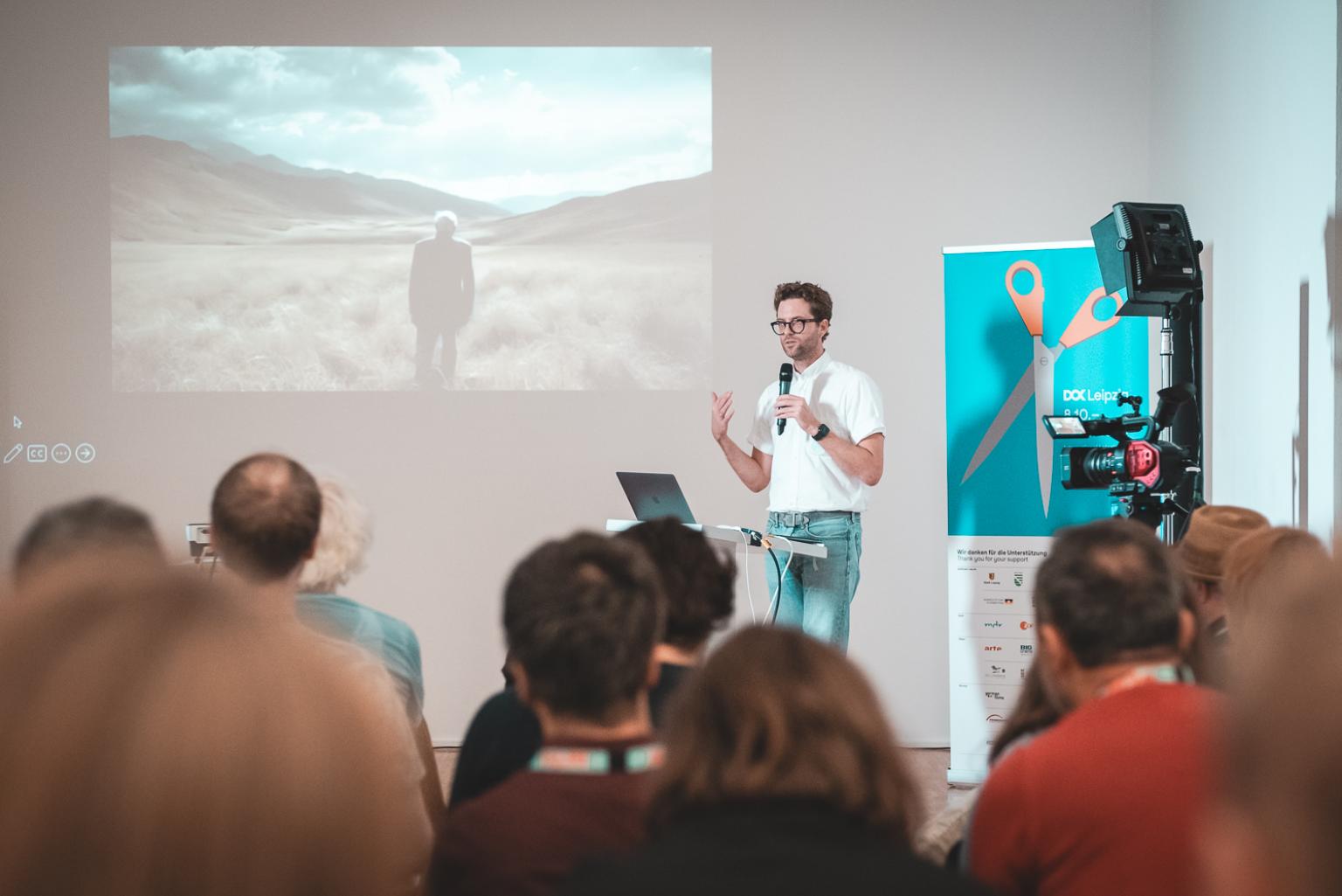 A speaker holding a presentation in front of an audience in a conference room.