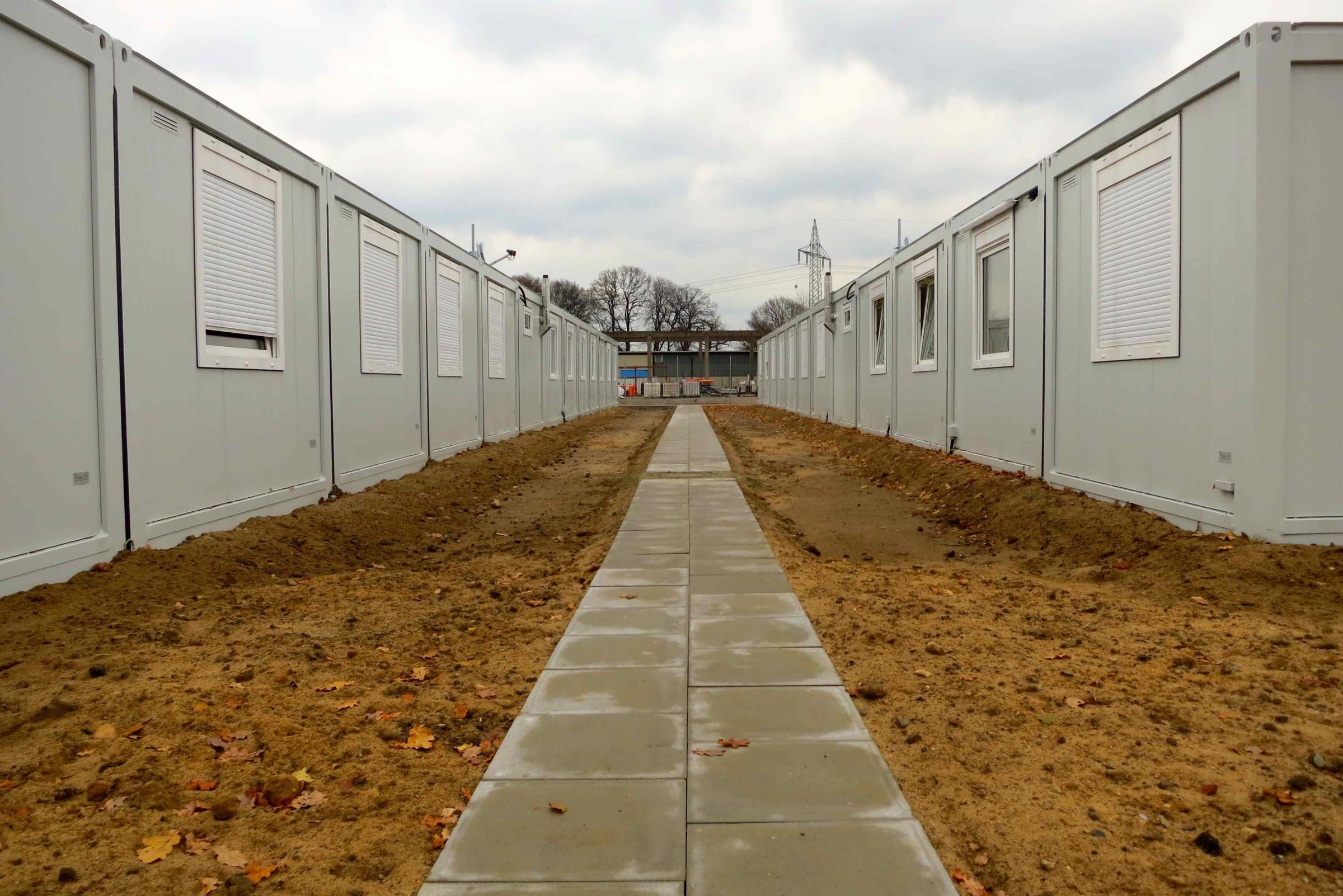 Ein Weg aus Pflastersteinen zwischen zwei Reihen aus Wohncontainern.