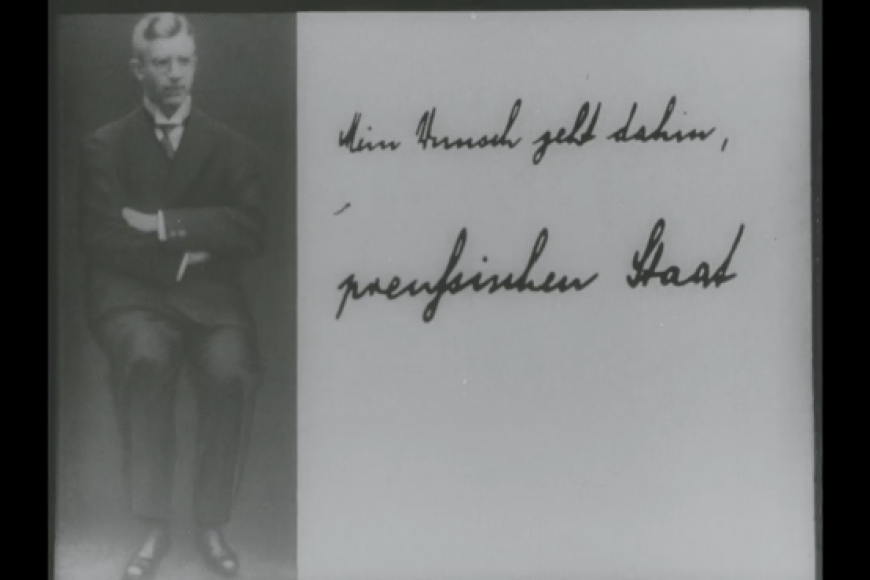 Filmstill: Ein Porträtfoto eines Mannes in den 30er Jahren. Rechts daneben steht in Handschrift  "Mein Wunsch geht dahin, preußischer Staat".